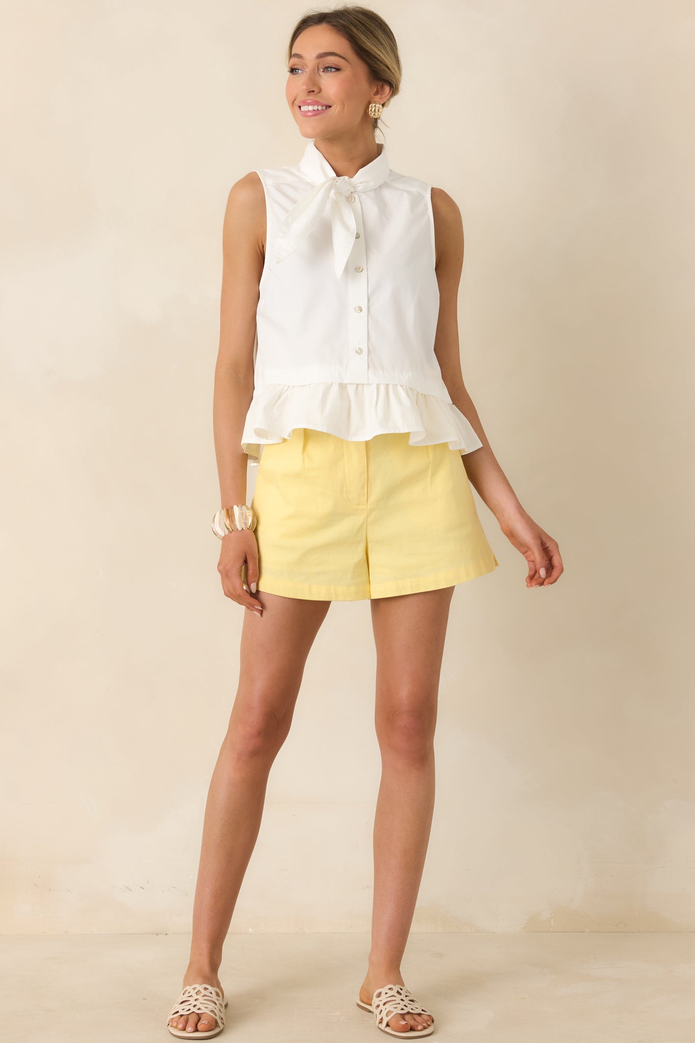 Polished sleeveless top featuring gathered ruffle hem and relaxed fit.