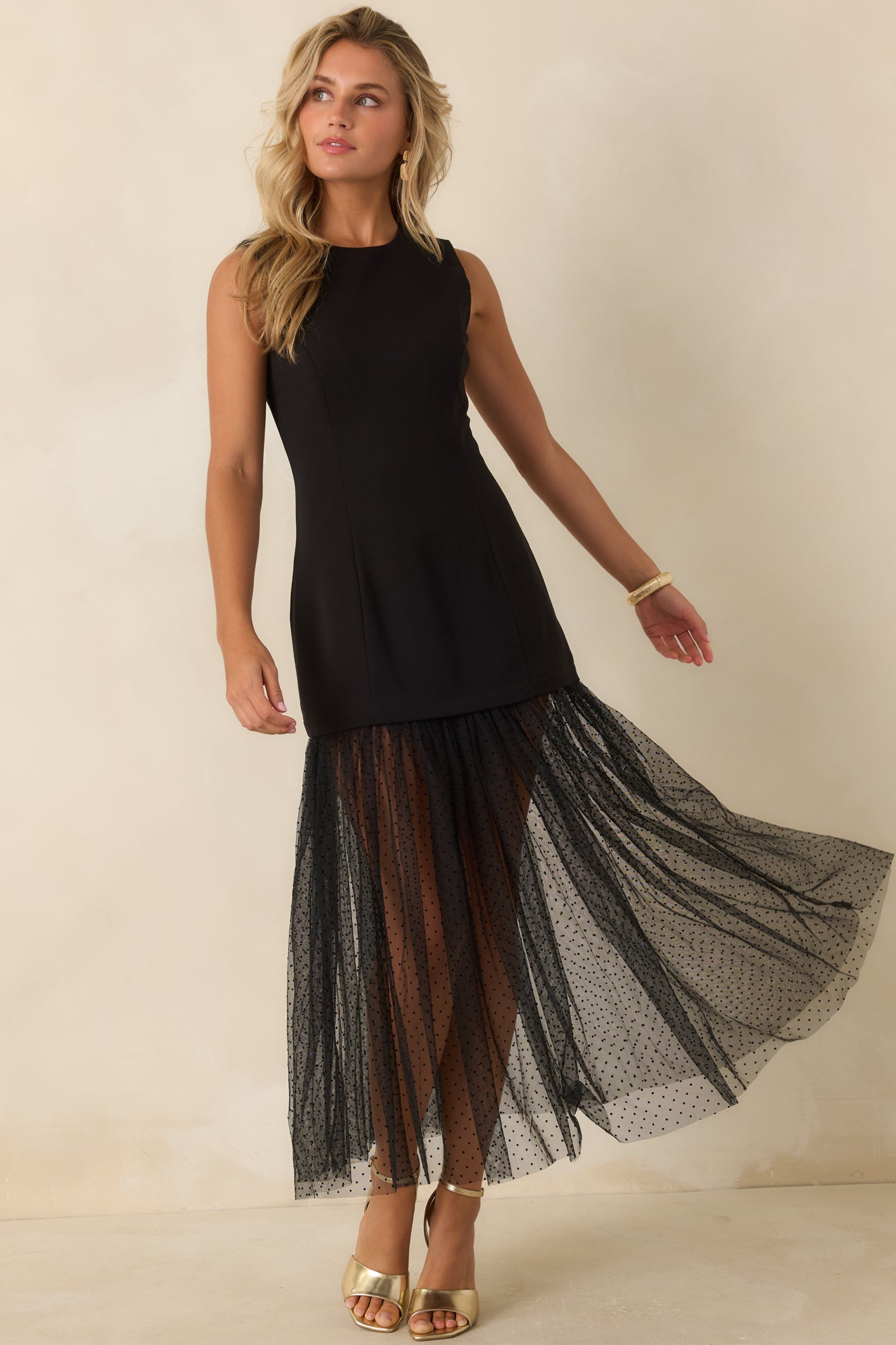 Elegant black stretch midi dress designed with sculpting princess seams, a sleeveless silhouette, and a sheer Swiss dot hem for added texture.