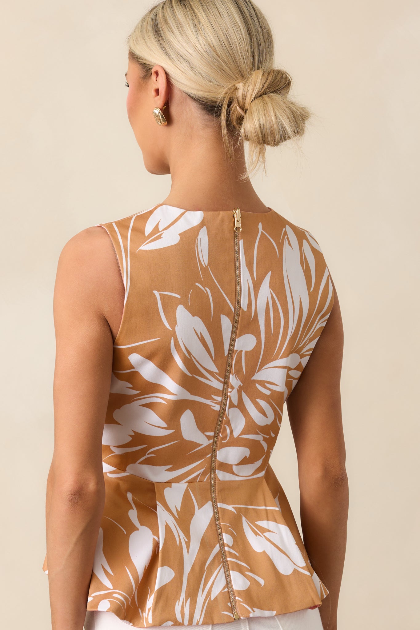 Rear view of the brown floral top showing gold zipper closure and sleeveless peplum silhouette.