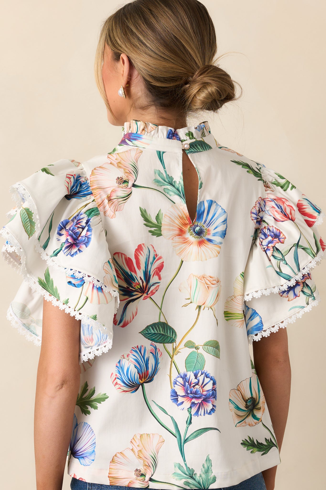 Rear view of the top featuring a back keyhole closure with faux pearl button and ruffle sleeves.