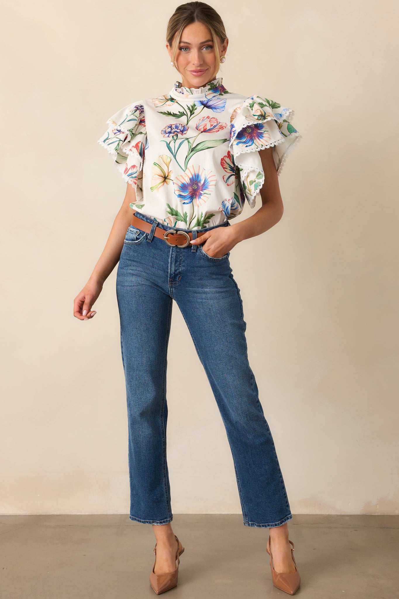 Ivory top with multicolor floral print, ruffle mock neckline, and short ruffle sleeves with eyelet trim.