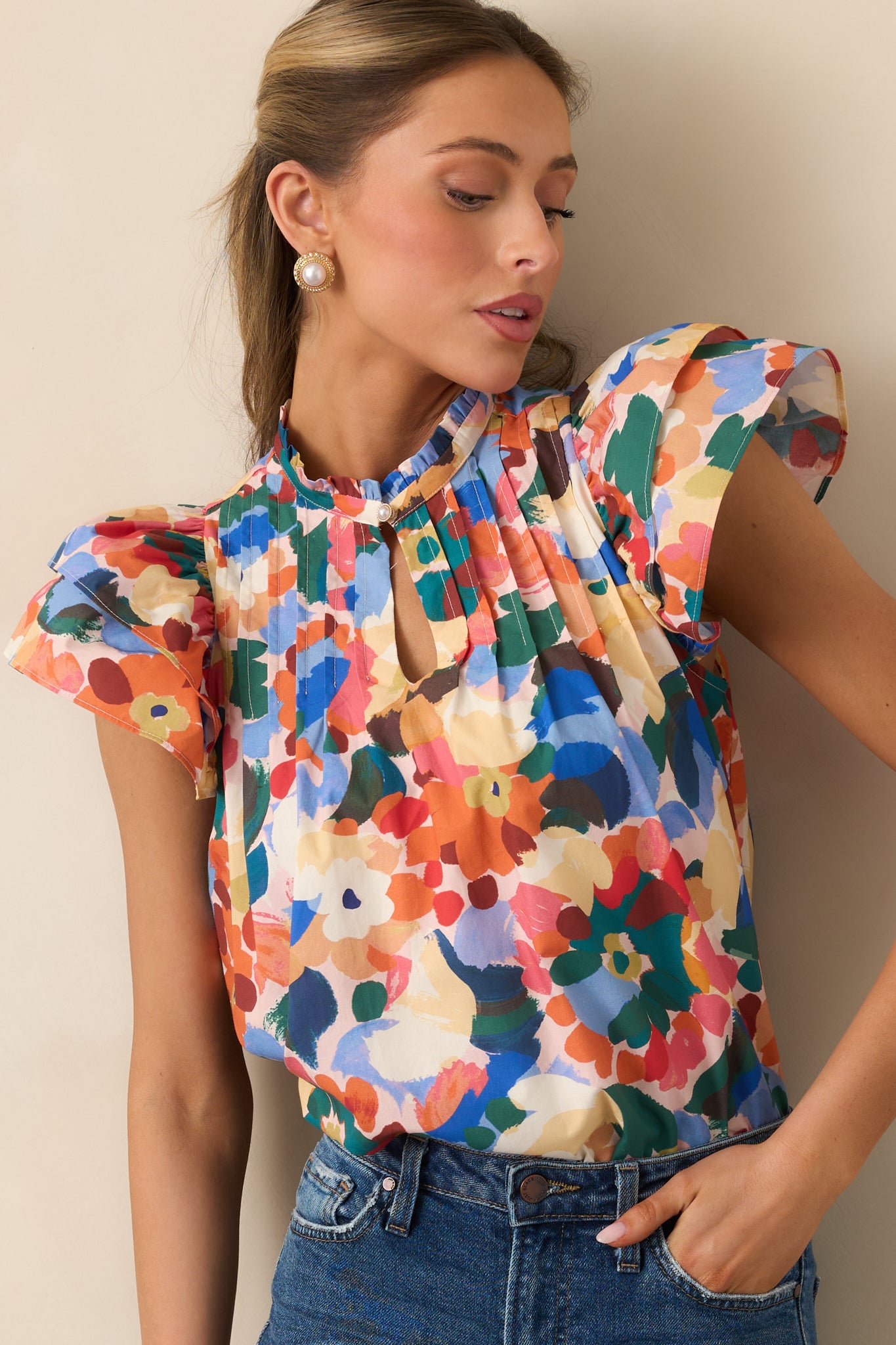 Detailed view of the orange multicolor floral print, ruffle neckline, and pintuck pleats.