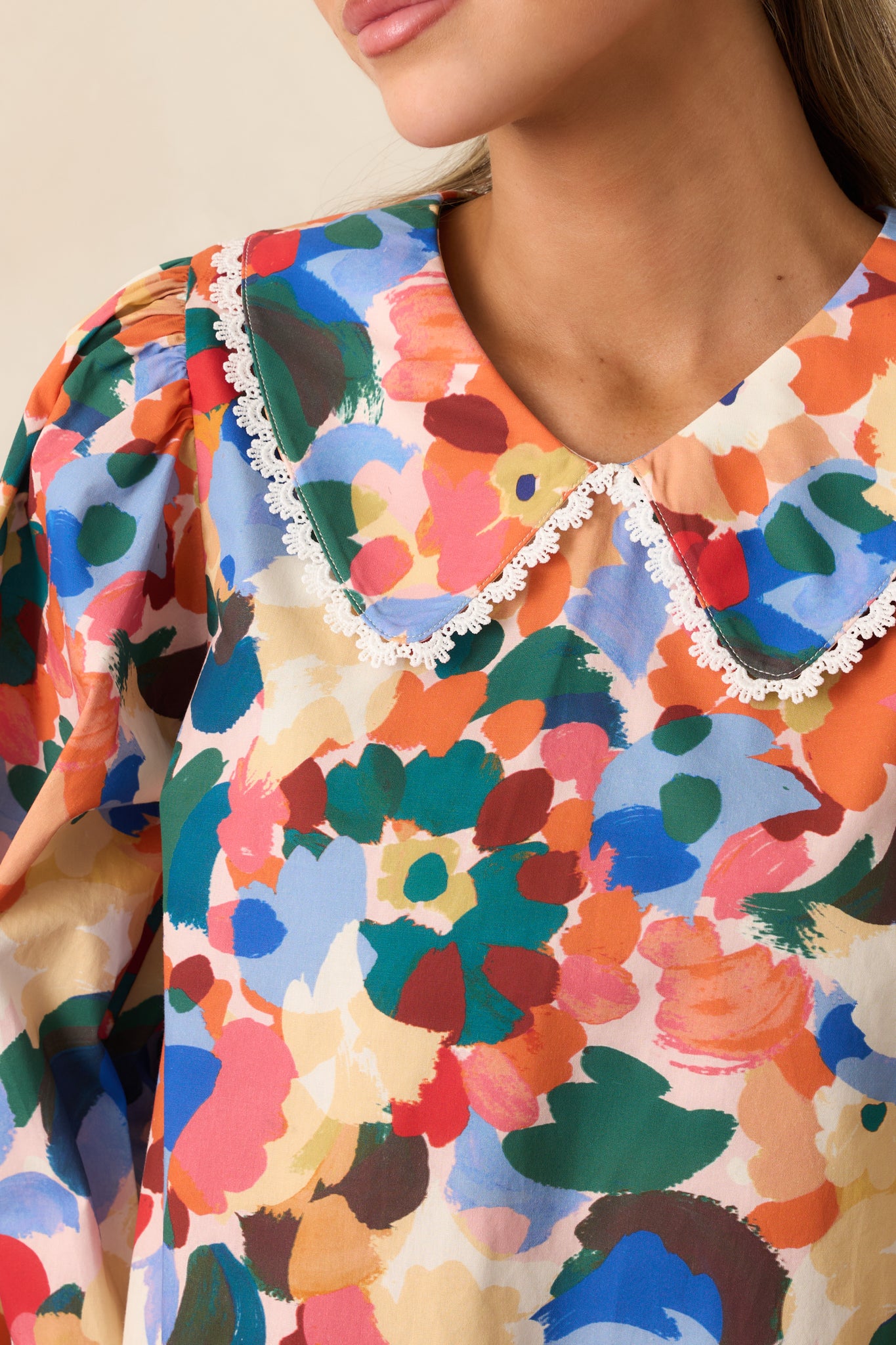 Detailed view of the orange multicolor floral print, lace trim, and peter pan collar.