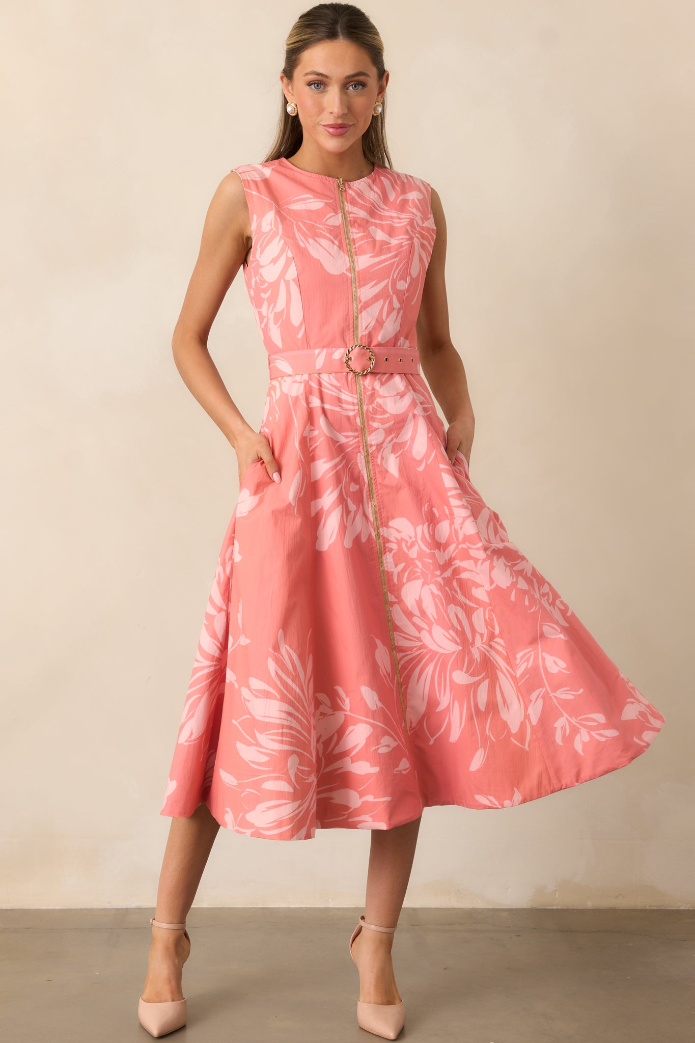 Midi dress with soft pink floral pattern, optional belt with gold buckle, and side pockets.