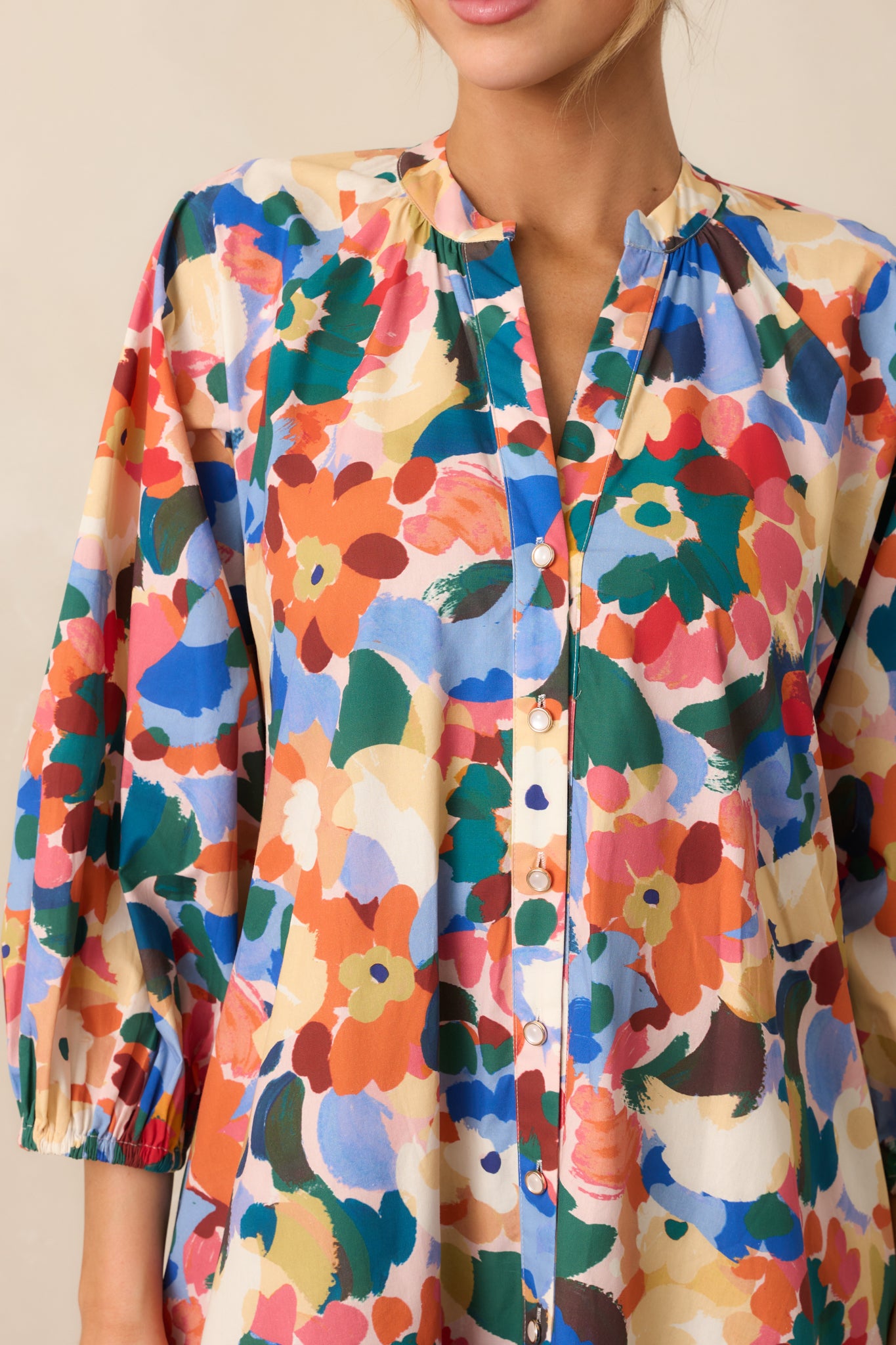Detailed view of the orange multicolor floral print, notch v-neckline, and button front.