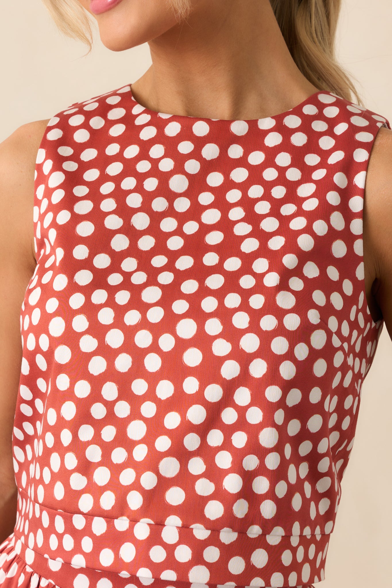 Detailed look at the brick red fabric with ivory polka dots and precise darted seams.