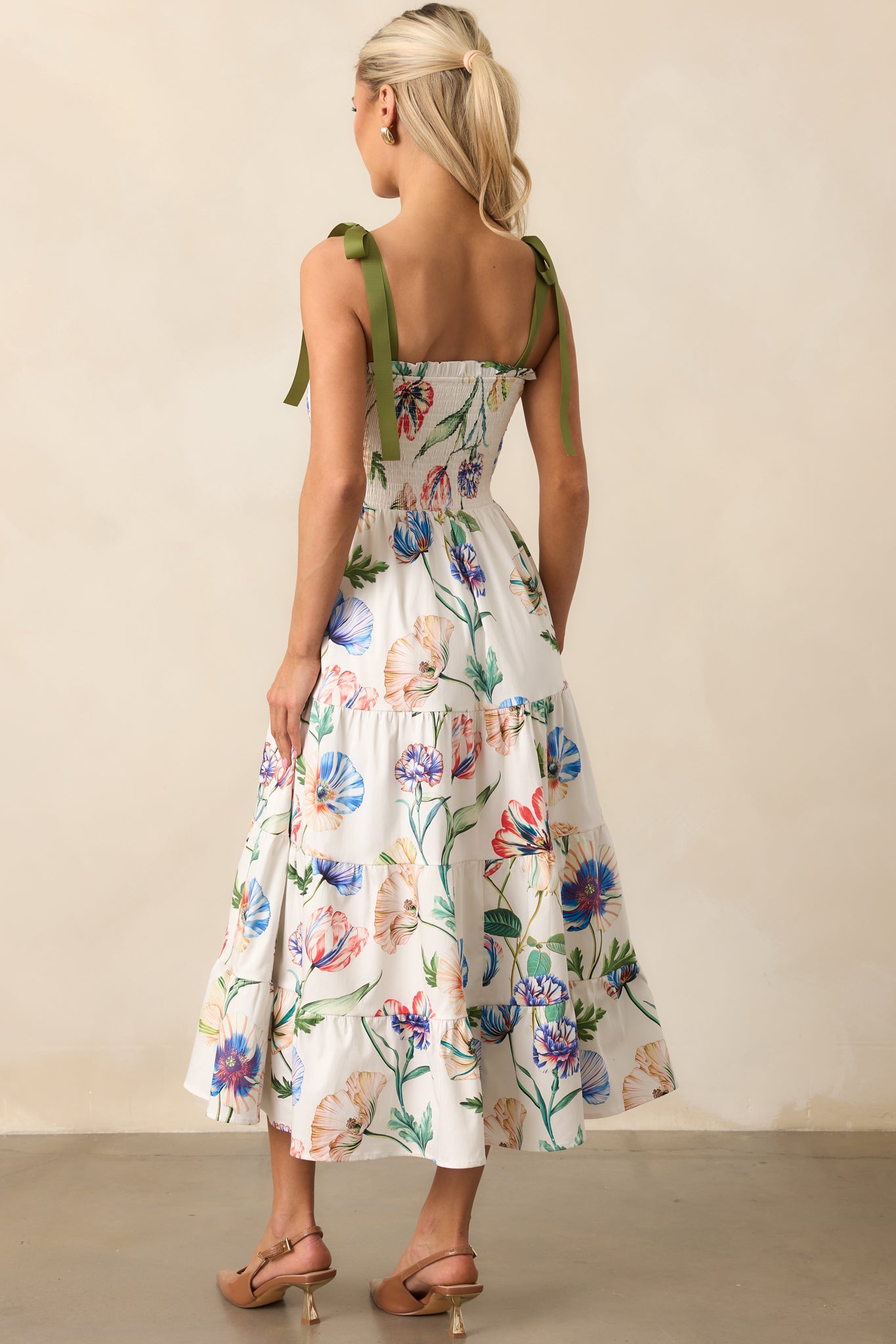 Rear view of the midi dress highlighting adjustable green bow straps and tiered skirt silhouette.