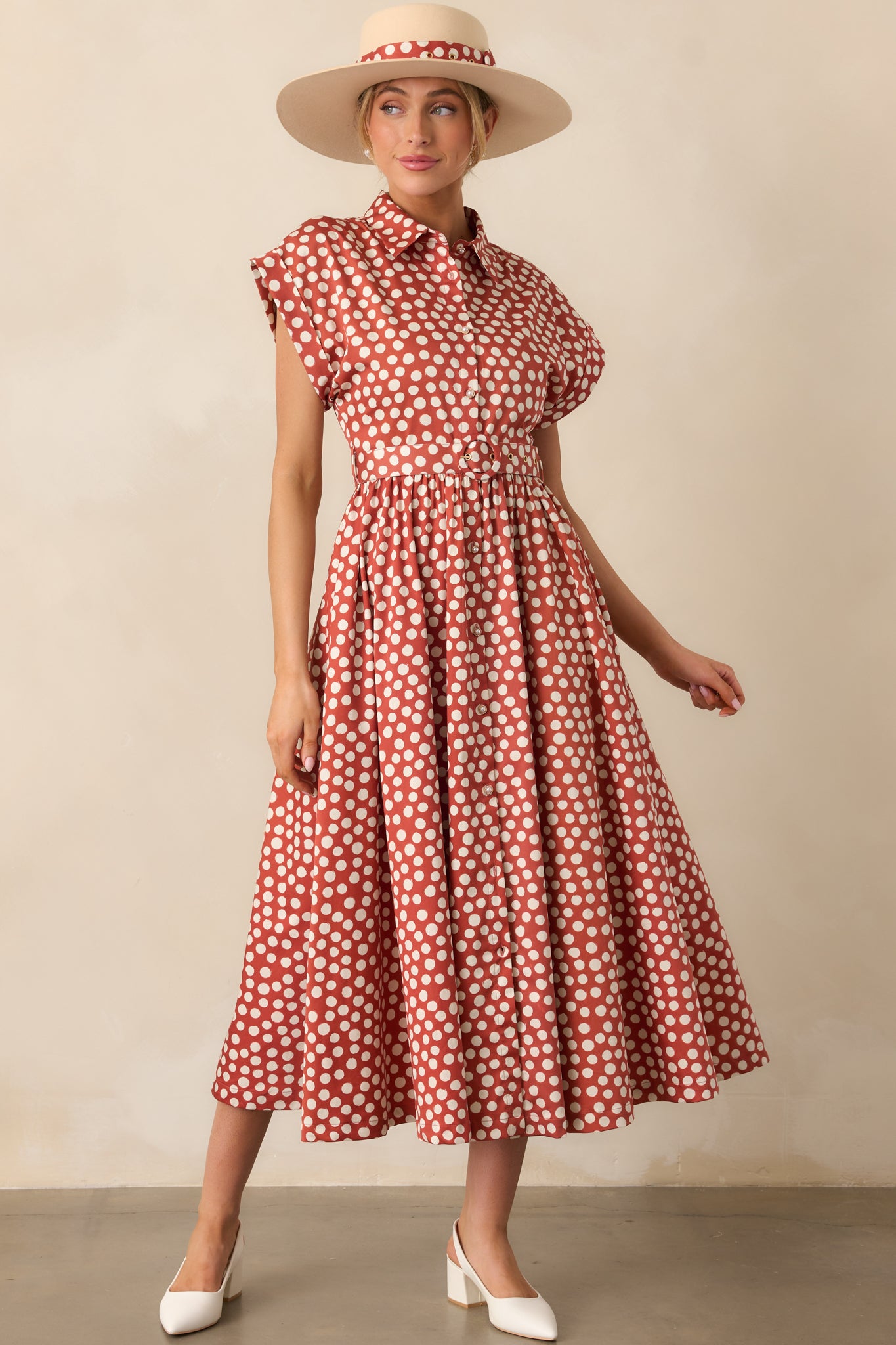 Brick red maxi dress patterned in ivory polka dots, styled with cuffed sleeves and functional front buttons.