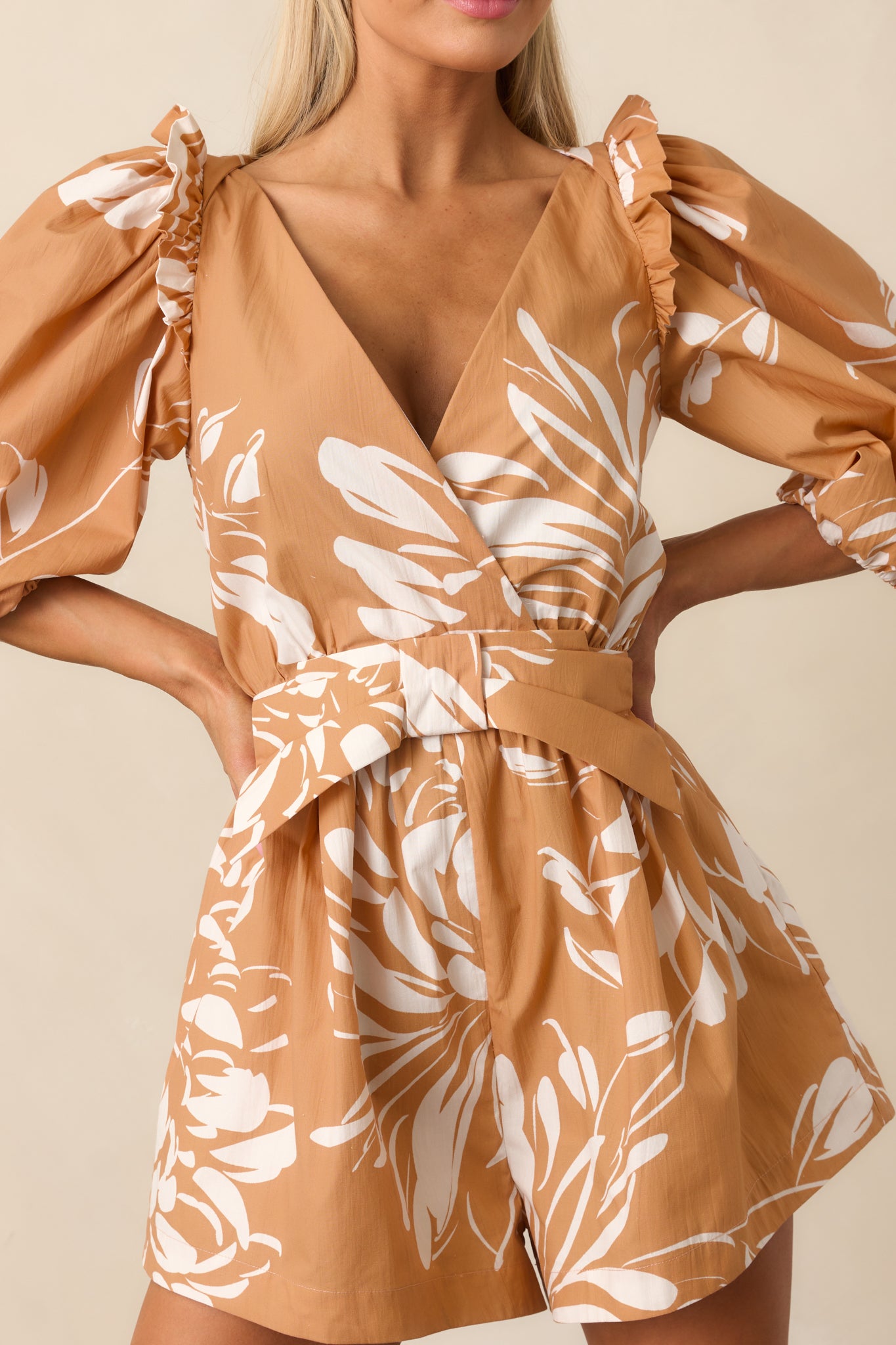 Detailed view of the fawn brown and ivory floral print with ruffle trim and bow accent.