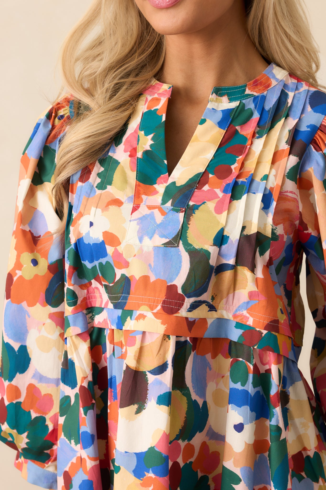 Detailed view of the orange multicolor floral print and front pintuck pleat detailing.