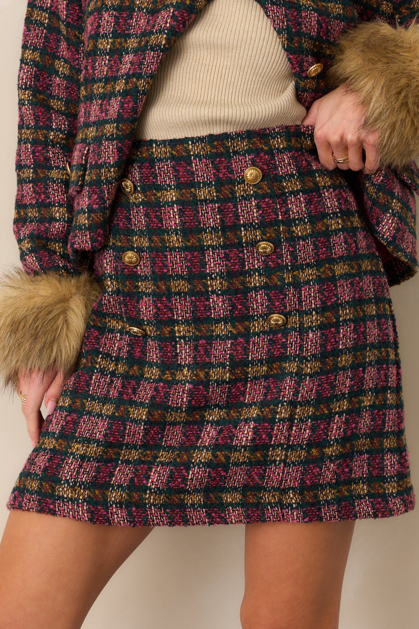 Close-up of the tweed fabric and button hardware showing the intricate plaid weave and rich texture.