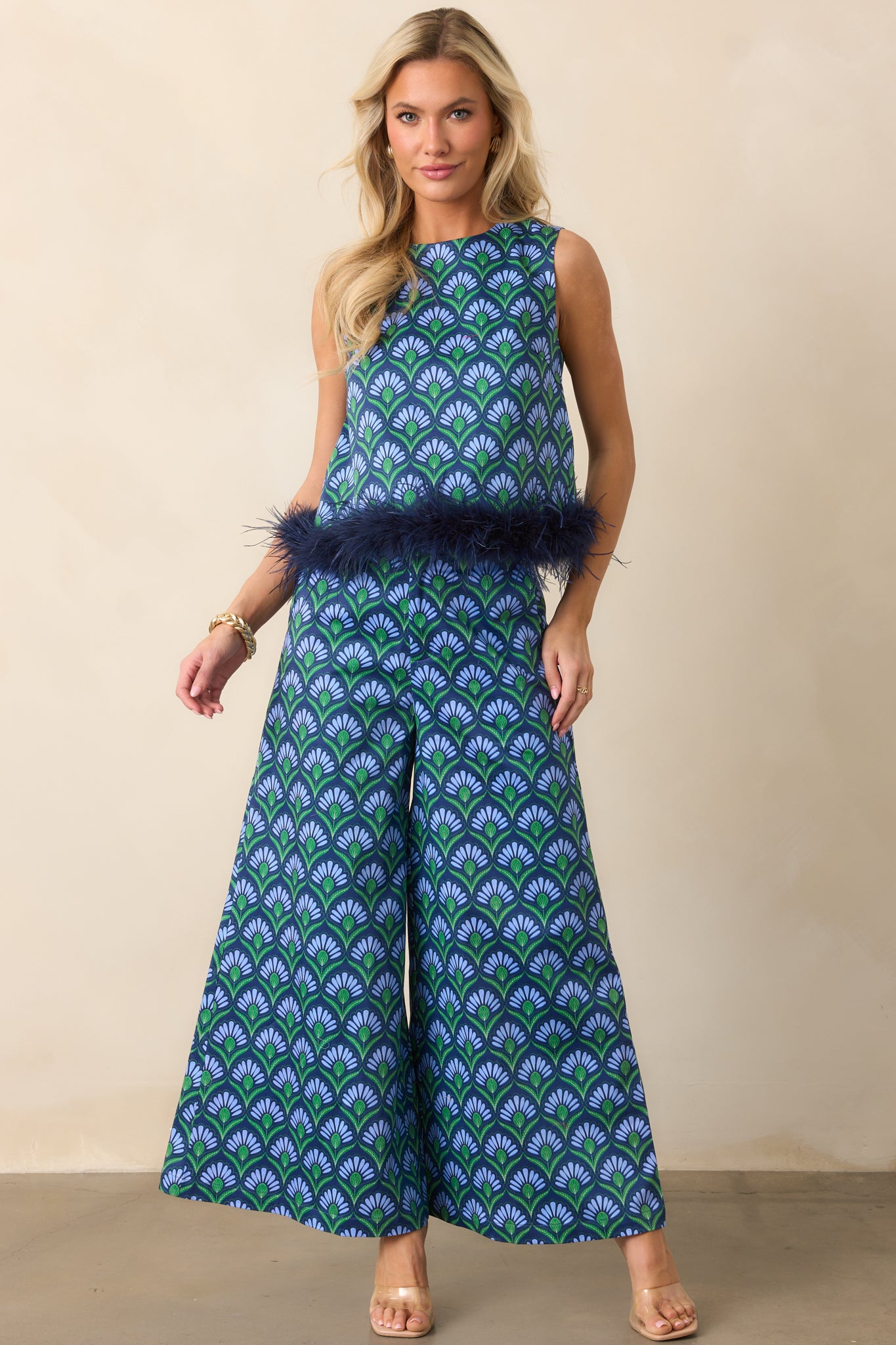 Front view highlighting a cropped blue geometric top with high round neckline and playful feather trim at the hem.