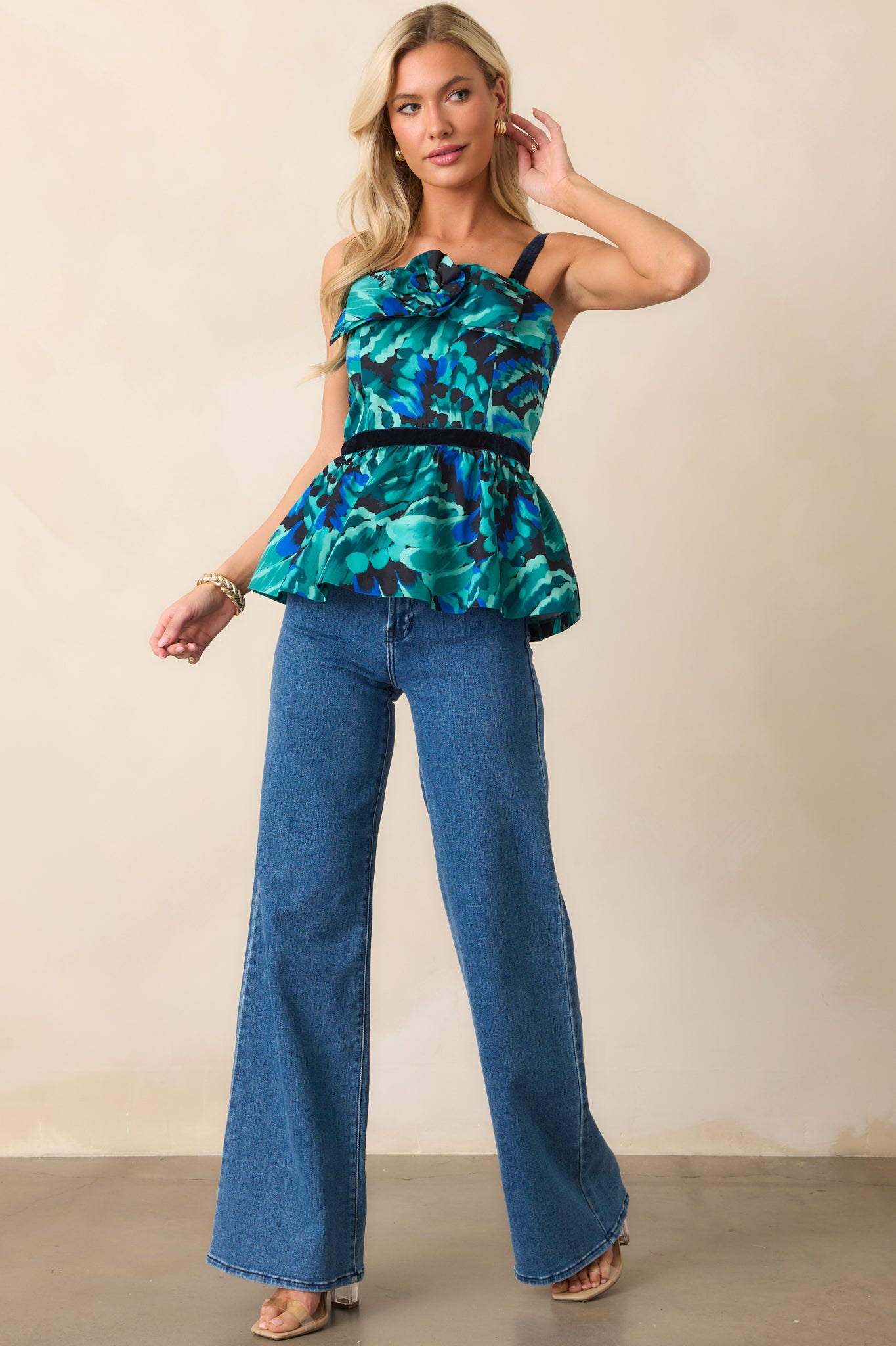 Sleeveless peplum top with a blue multicolor abstract print, straight neckline, and fitted bodice with velvet waist banding.