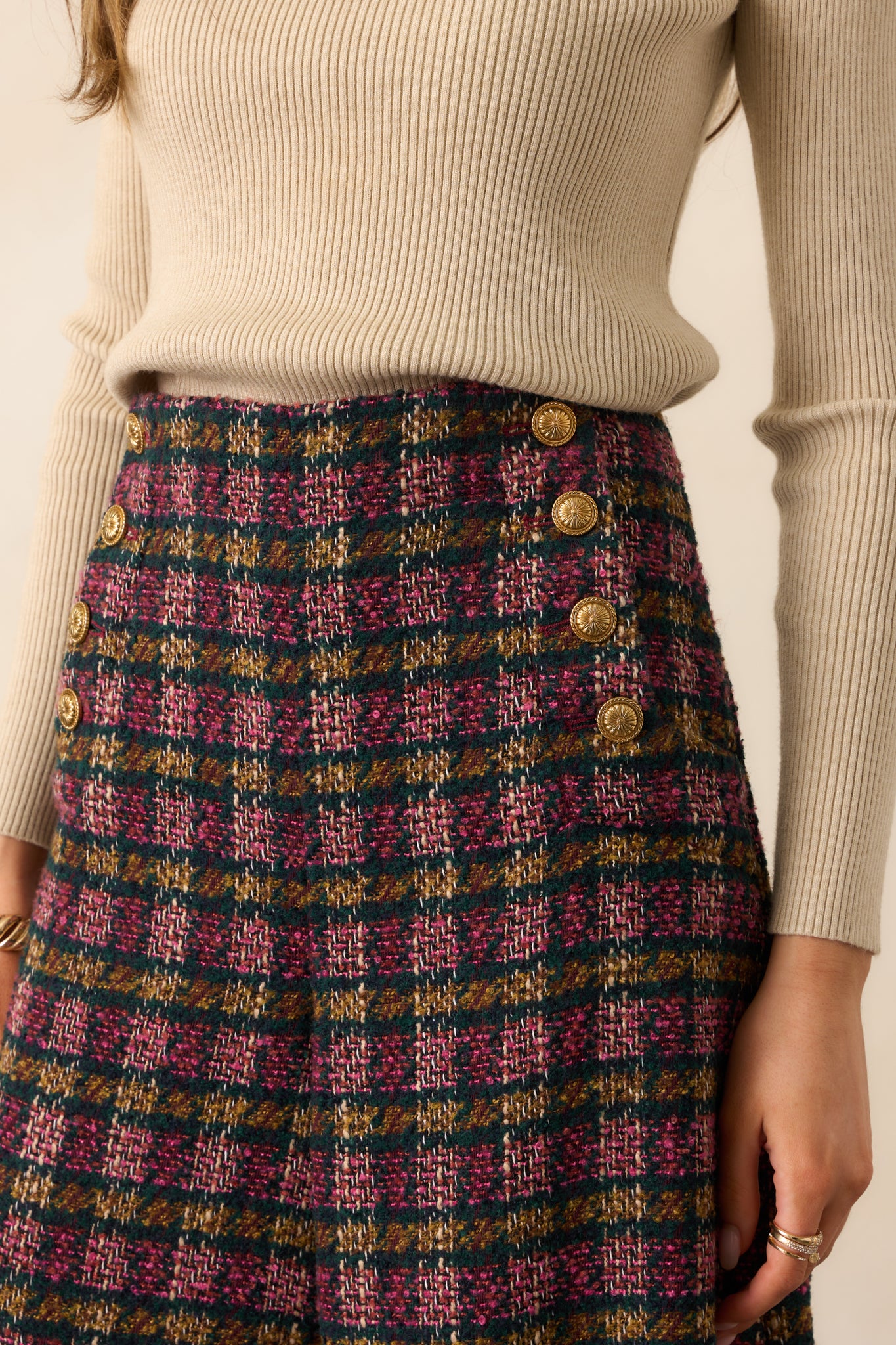 Close-up of the gold crest buttons and tweed fabric showing the intricate plaid weave and color contrast.