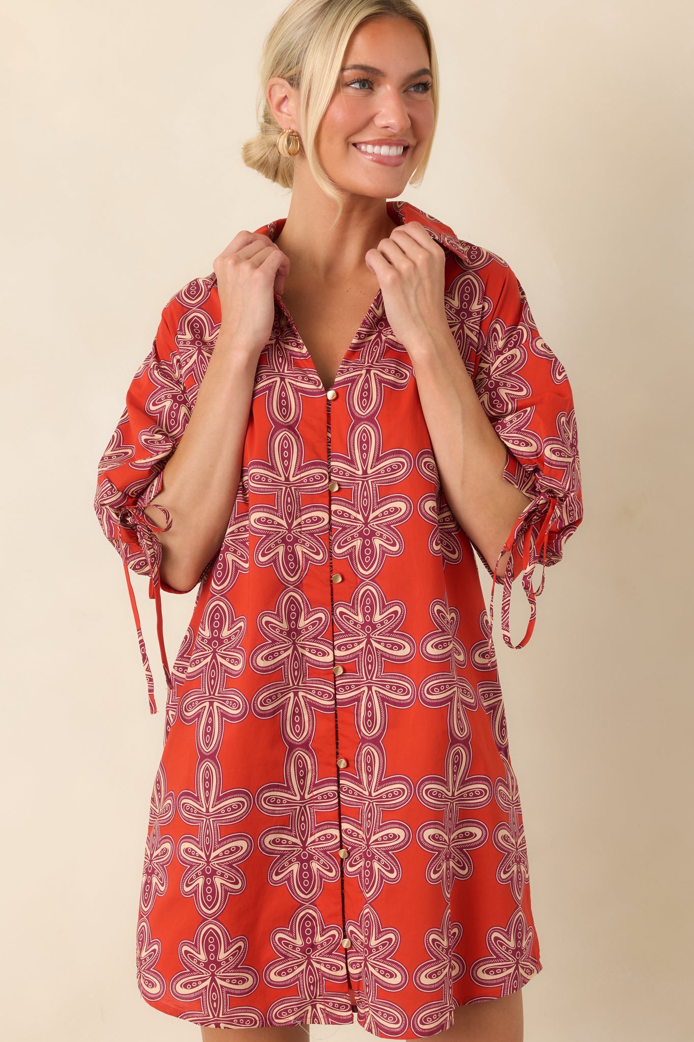 Tie details on the puff sleeves add a playful accent to this brick red and burgundy mini shirt dress.