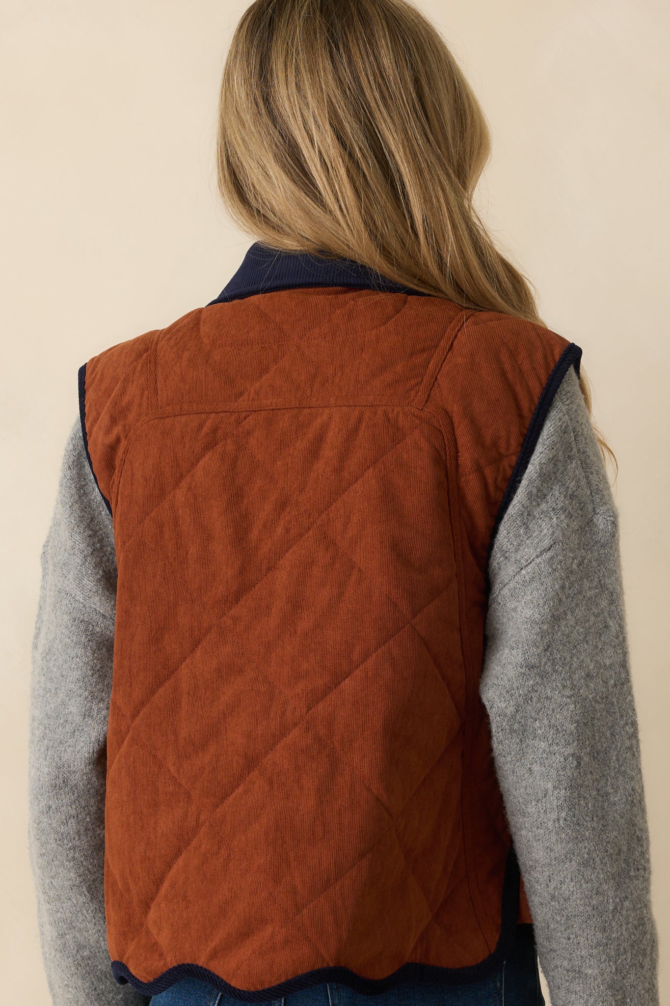 Rear view of quilted corduroy vest showing diamond stitching and clean scalloped hem.