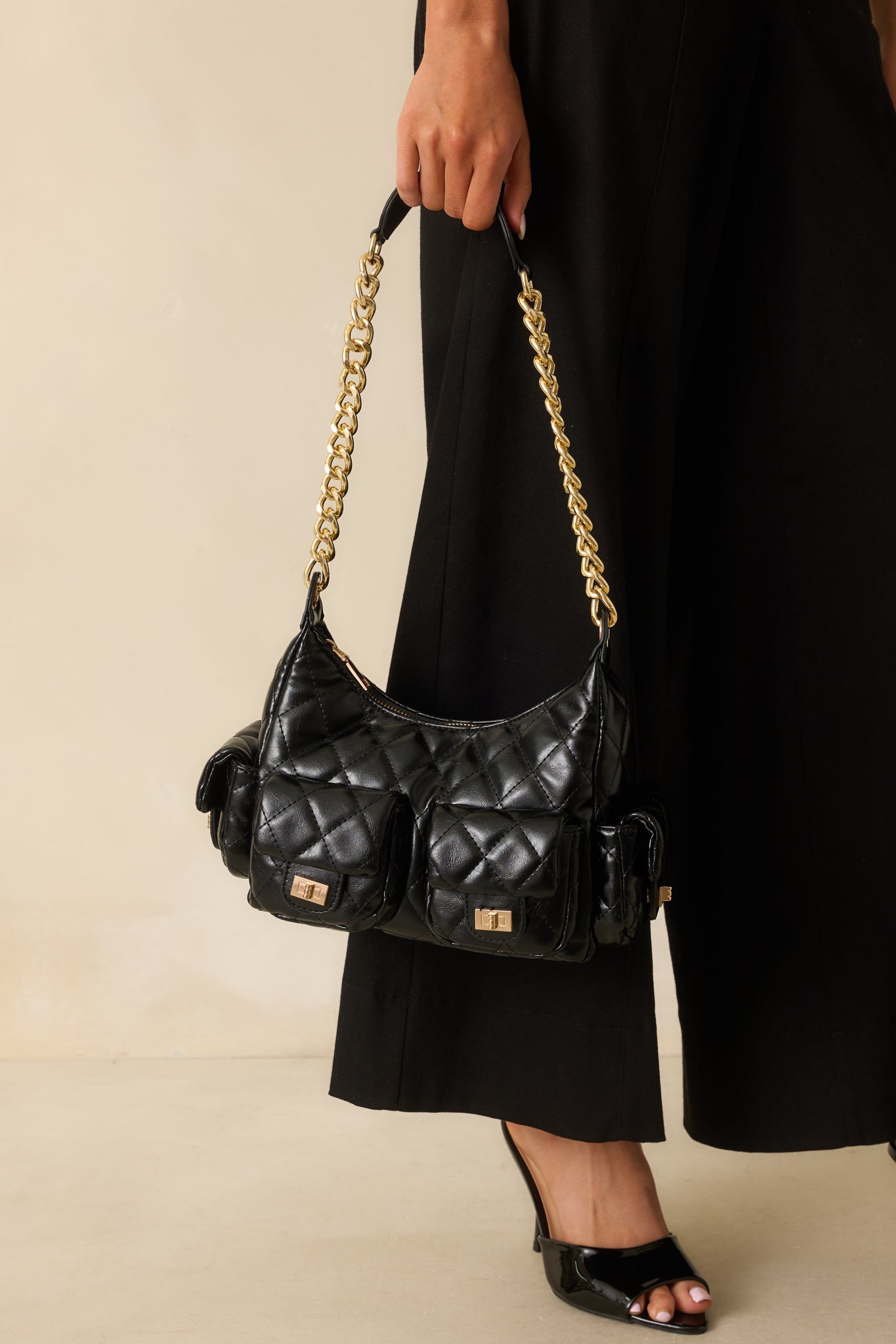 A cropped angled view of the handbag focusing on the quilted faux leather texture and gold chain detail.