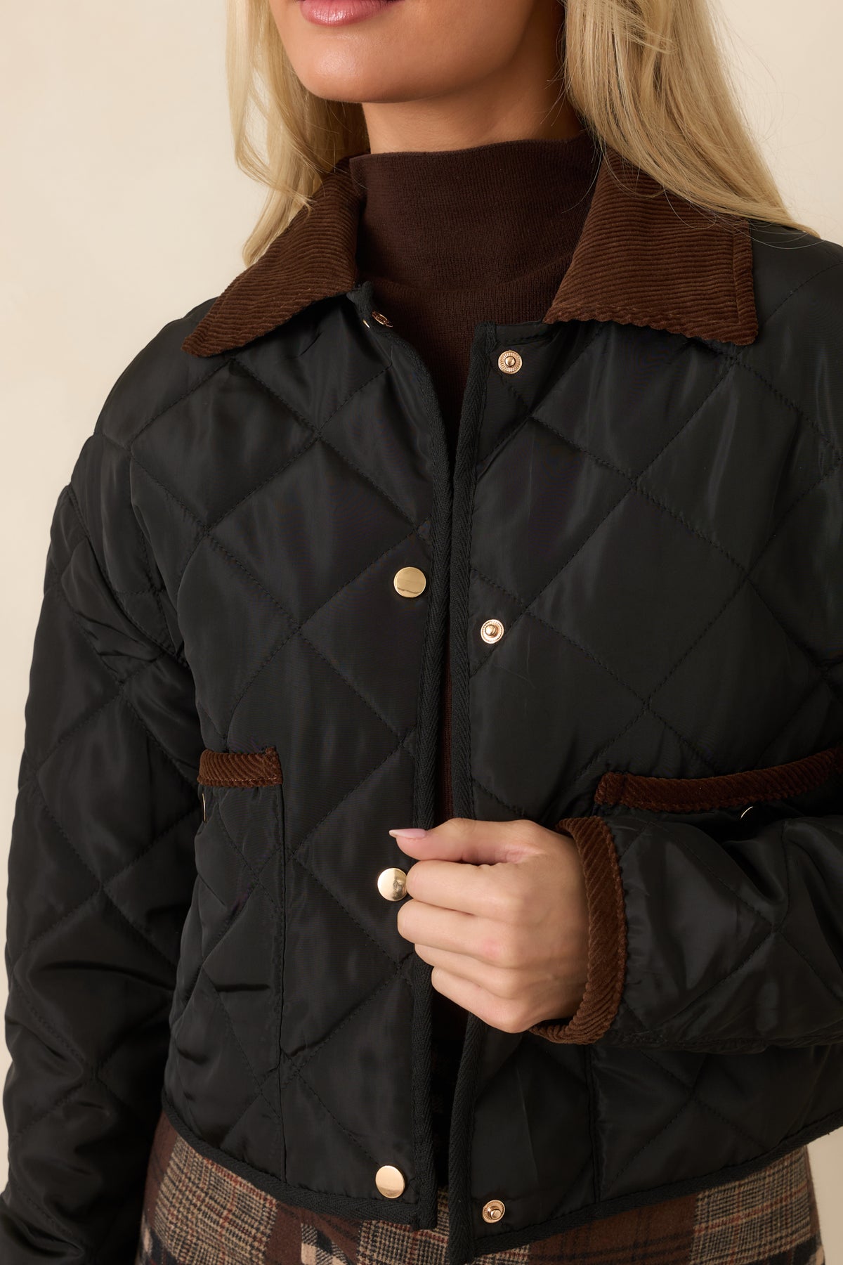 Close-up of the diamond stitching, contrasting brown collar, and snap-front hardware on the quilted jacket.