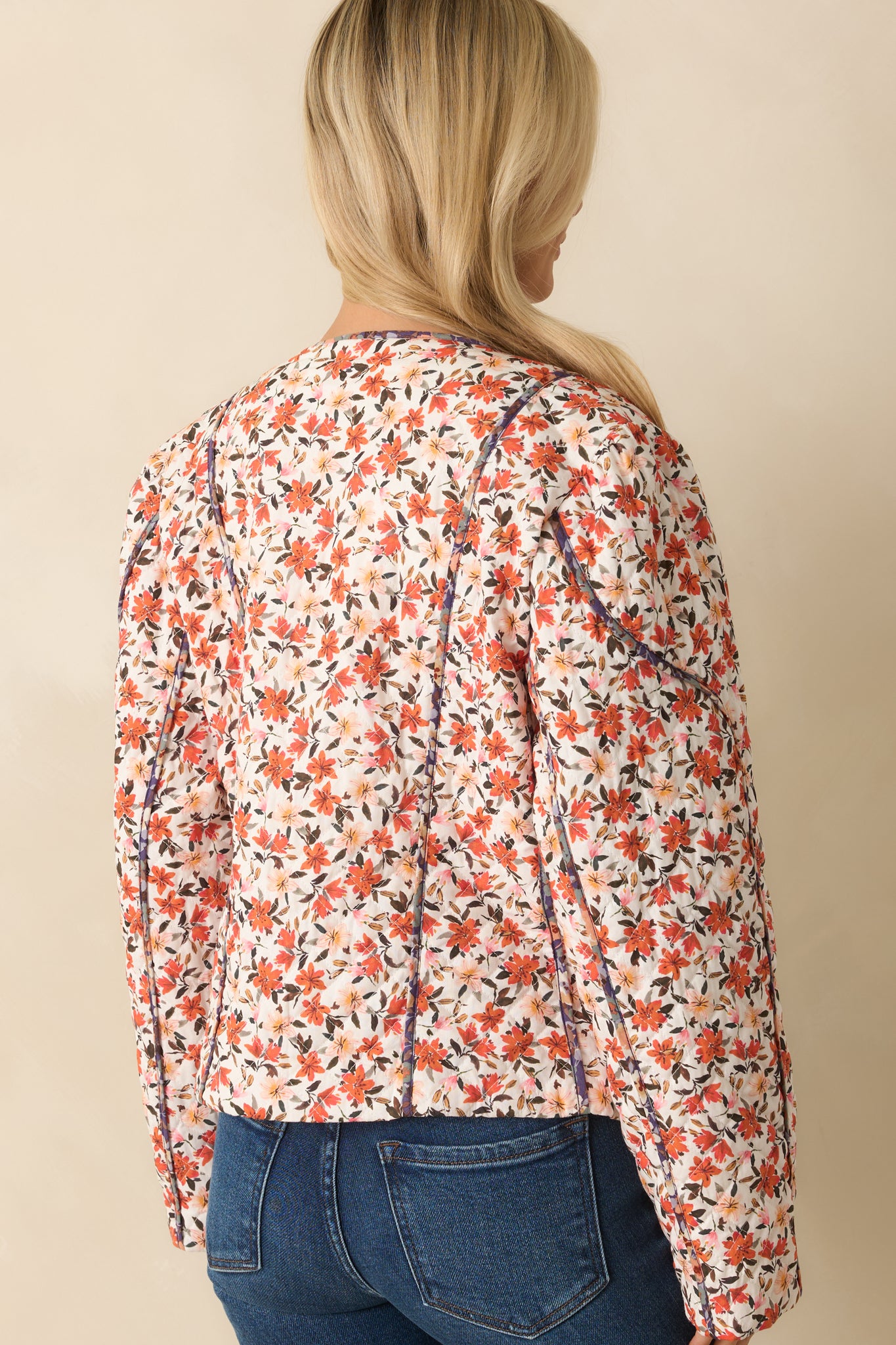 Rear view of the quilted jacket showing vertical seam paneling, long sleeves, and contrast piping along edges.