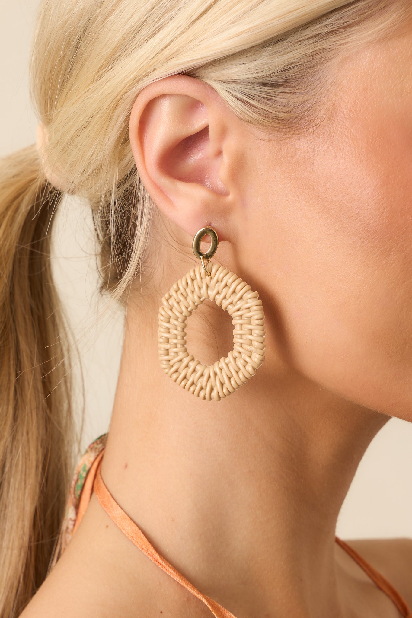 Tight detail of the textured raffia-inspired hexagon and the smooth, reflective gold oval stud with secure post backing.