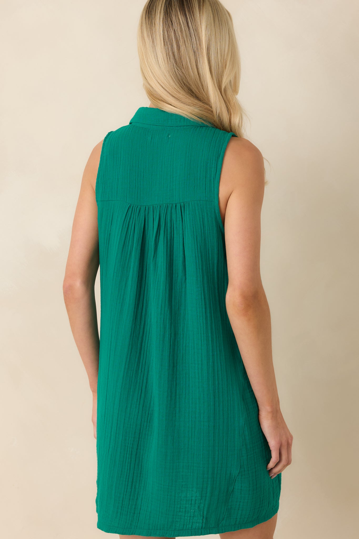 Back view of the rainforest green mini dress featuring the sleeveless silhouette, relaxed fit, and soft textured cotton fabric.
