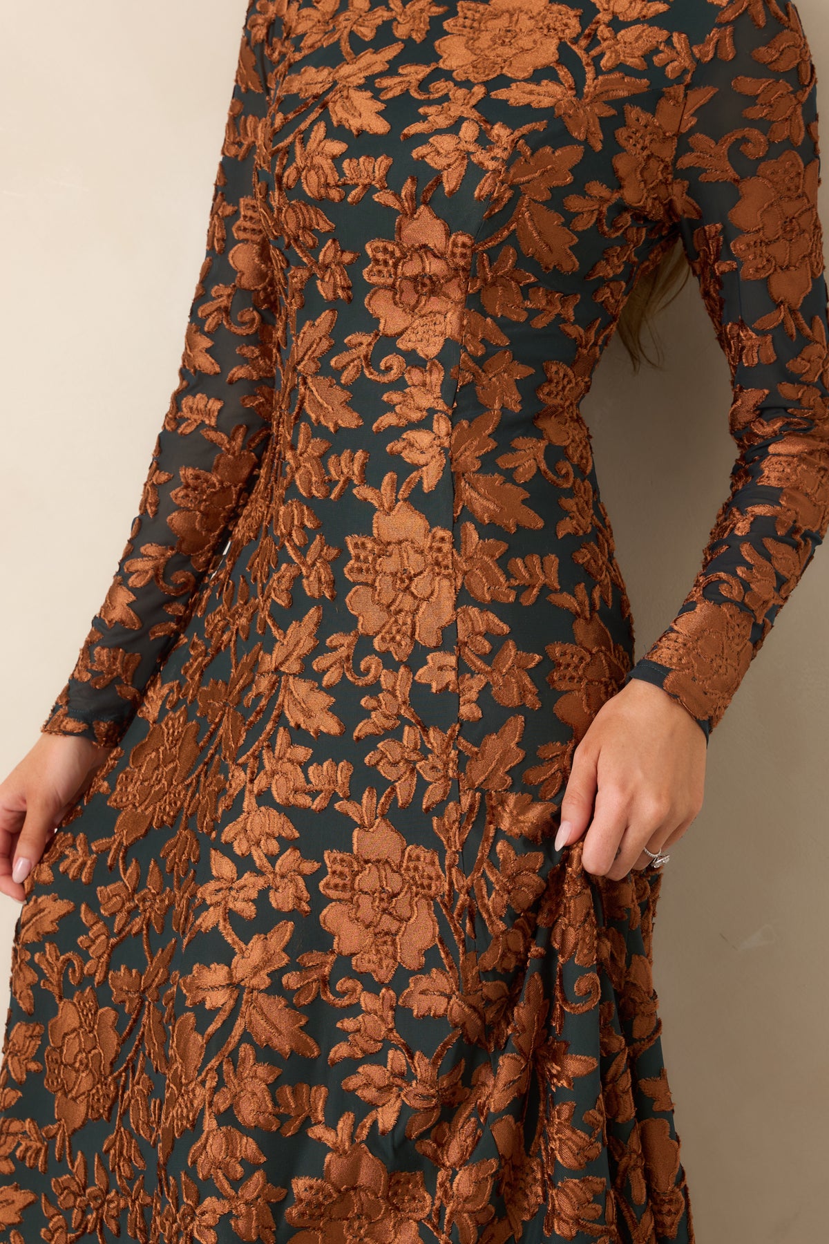 Close-up of the raised copper floral motifs against the deep green fabric, highlighting the dimensional texture of the dress.