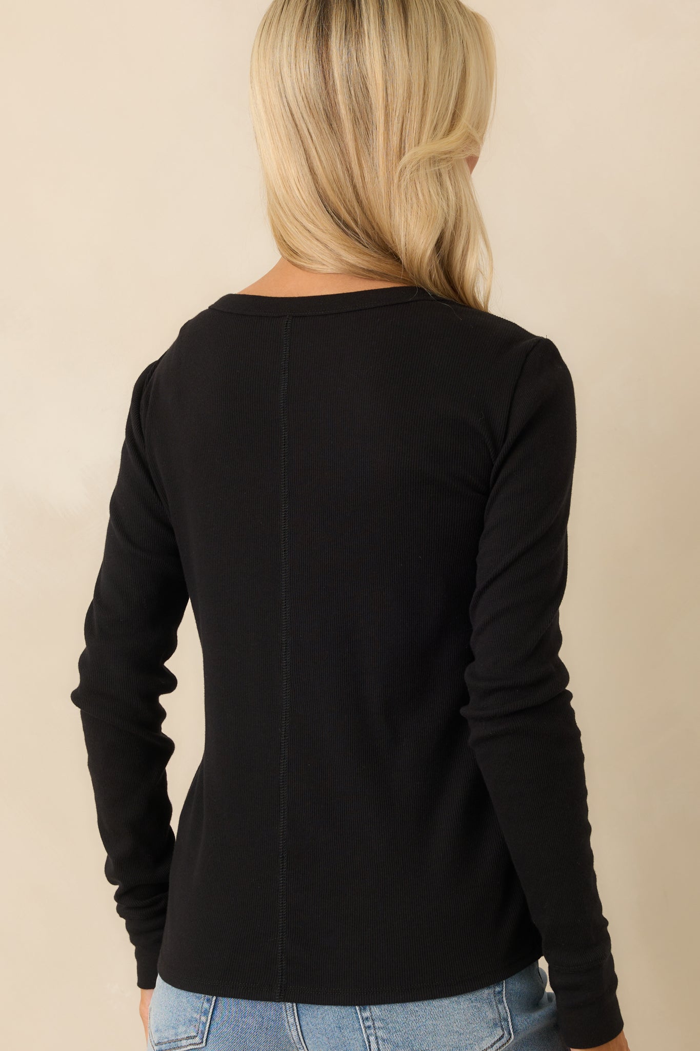A view from behind showing the back center seam detail, long sleeves, and consistent ribbed texture of the black top.