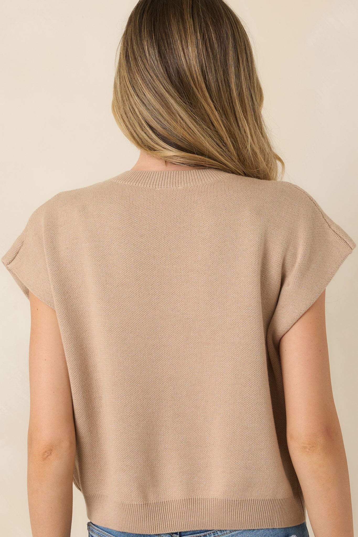 Rear view of the beige lightweight knit sweater featuring cap-style sleeves and a relaxed silhouette.
