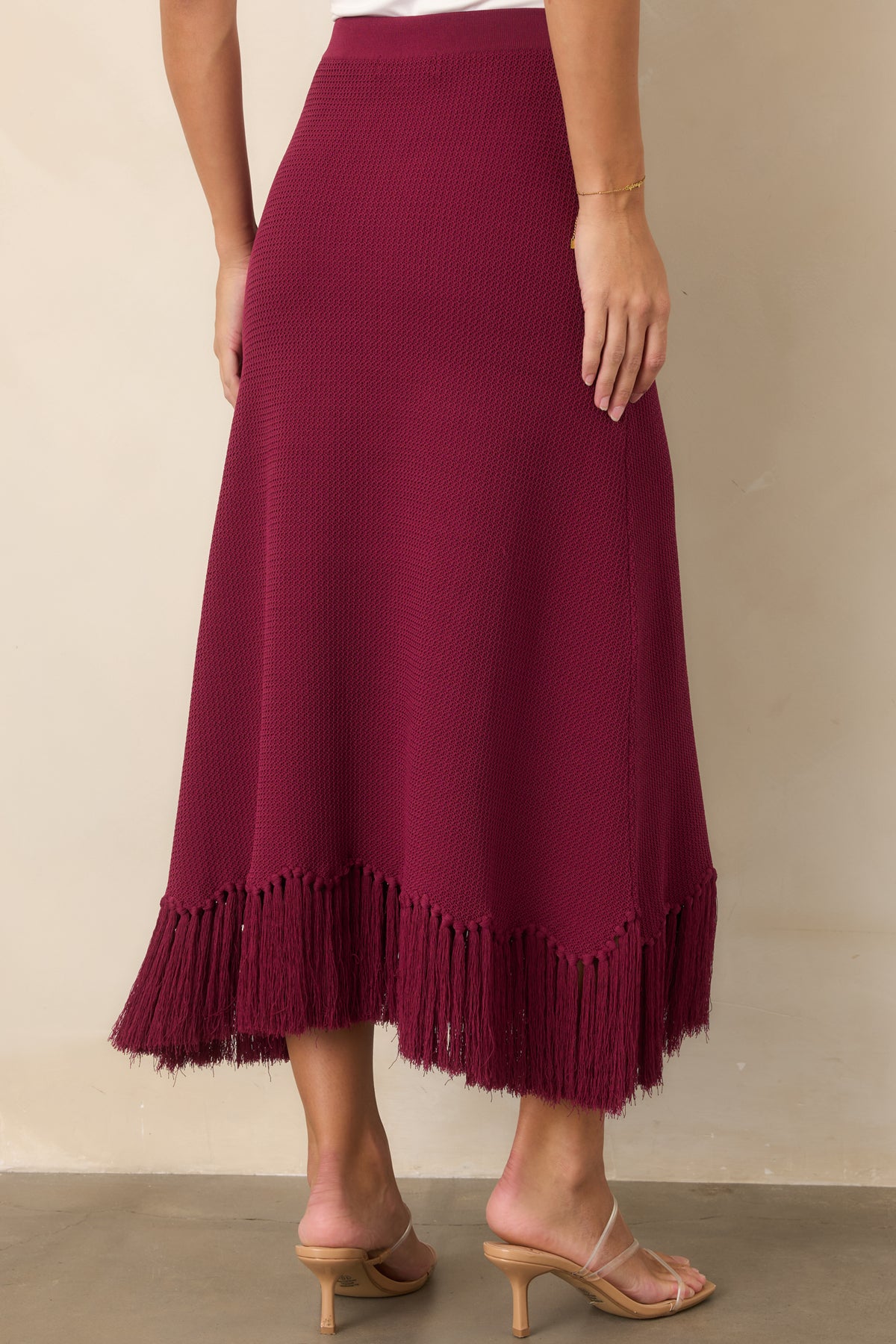Rear view of the berry textured knit skirt with a long silhouette and fringe-trimmed hem.