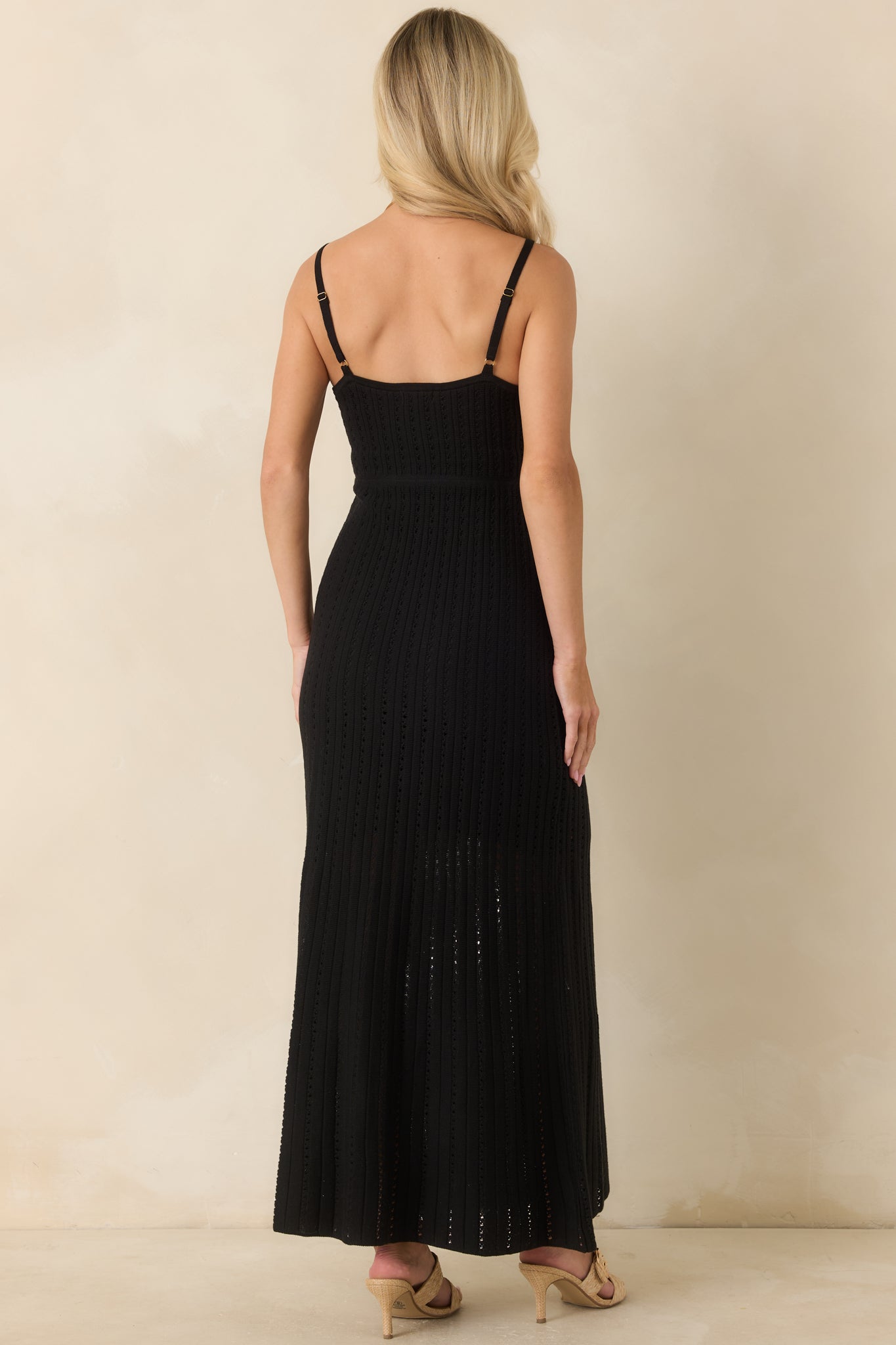 Rear view of the black crochet maxi dress showcasing the airy open-knit design, adjustable spaghetti straps, and fitted silhouette.