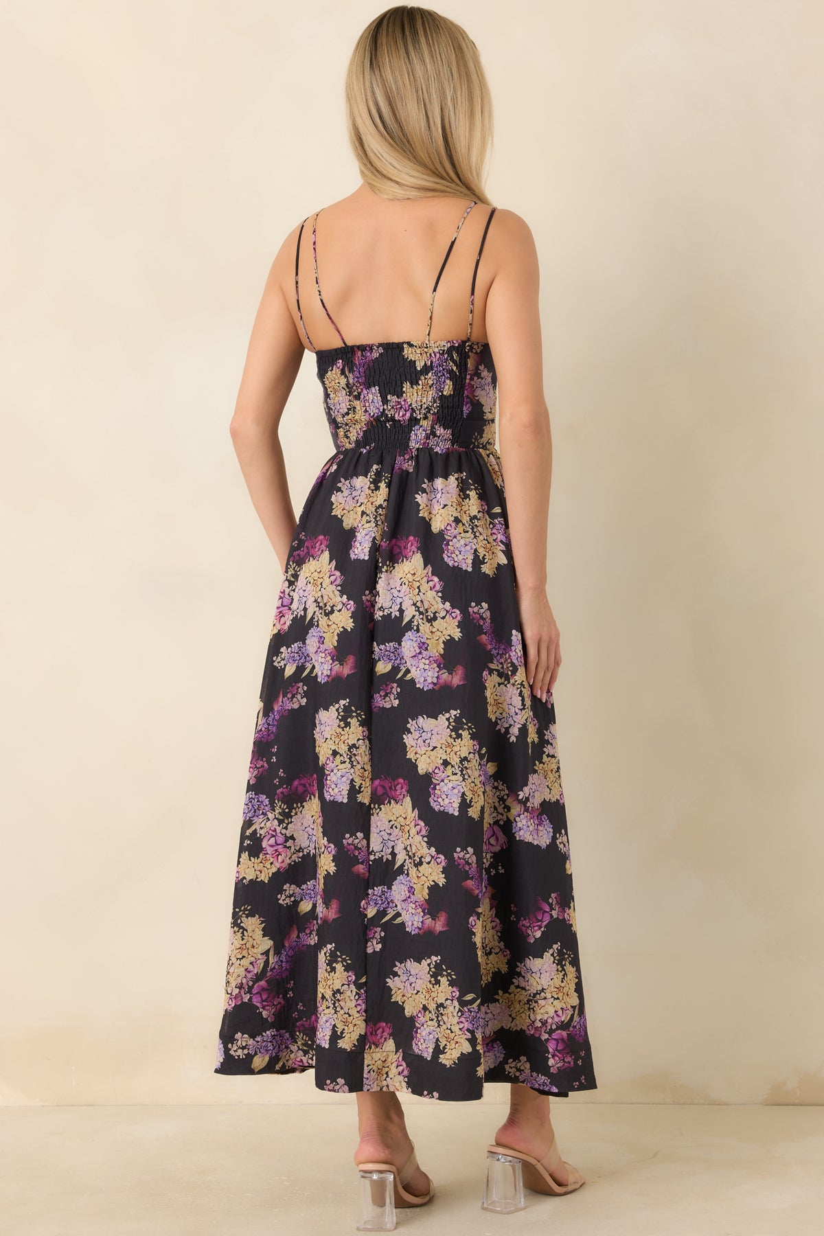 Rear of the black floral midi dress showing the smocked back bodice, adjustable tie straps, and gathered skirt.