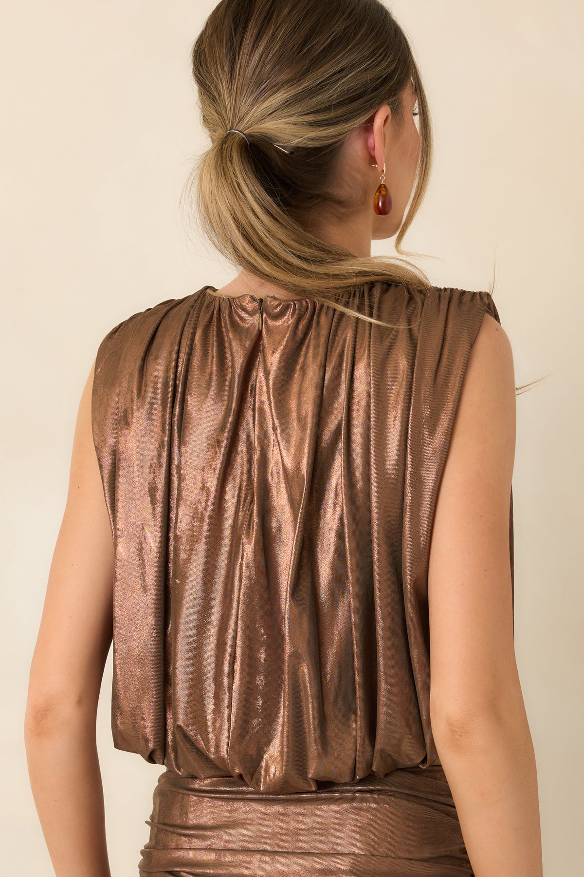 Rear of the bronze sleeveless top showing the concealed back zipper and gathered cropped bubble hem.