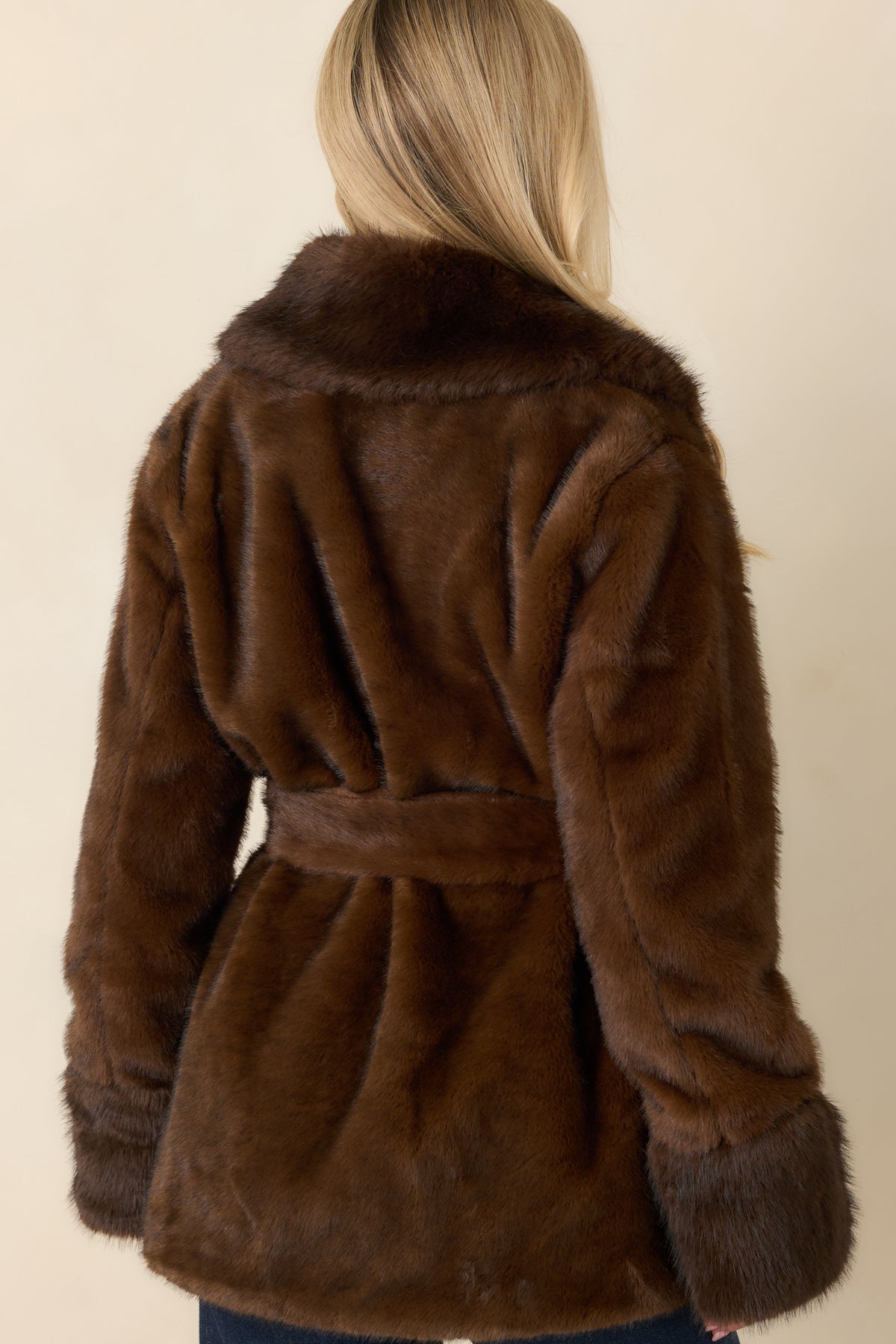 Rear of the brown faux fur coat showing its plush texture, long sleeves, and hip-length cut.