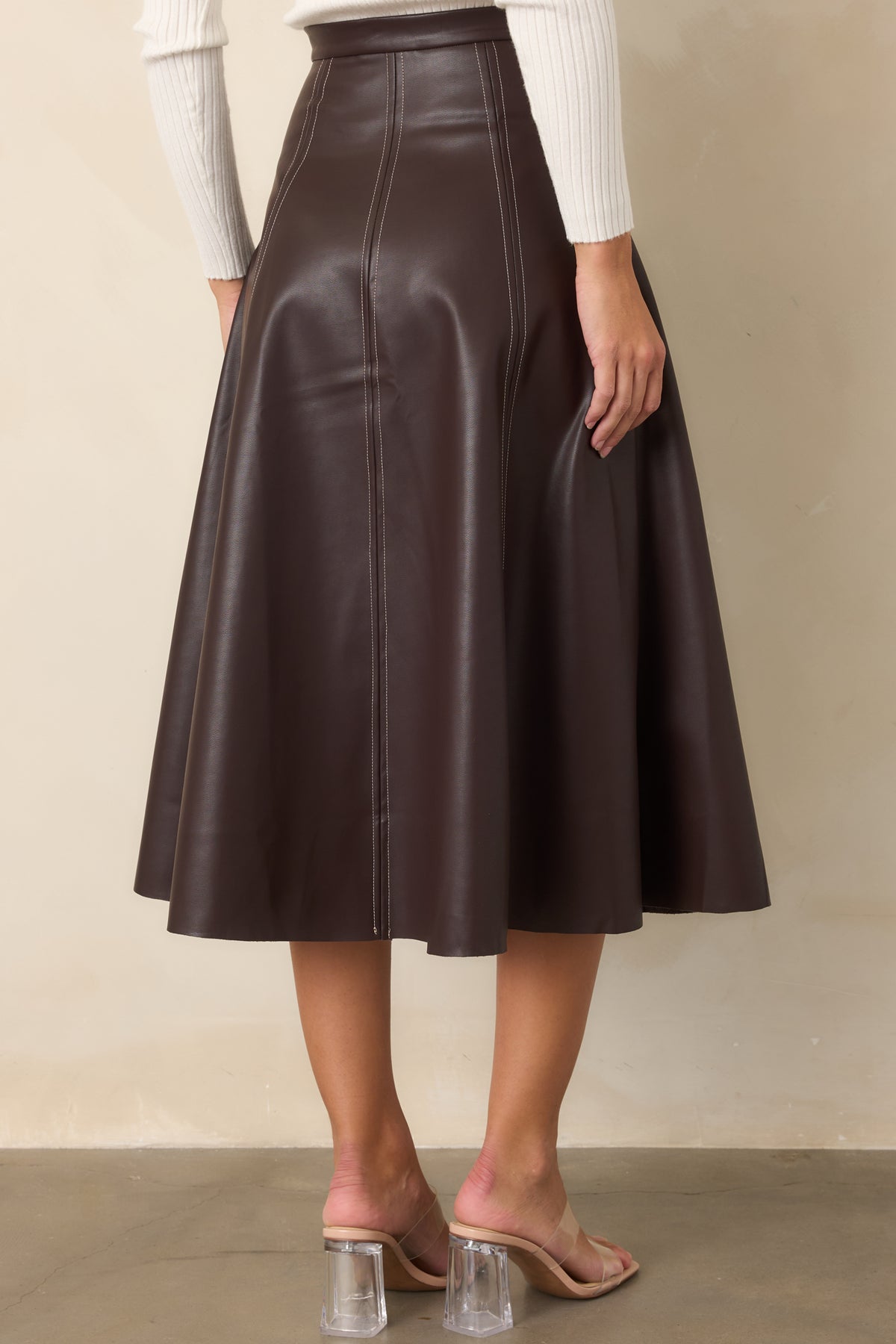 Rear of the brown faux leather skirt showcasing the defined waistband, paneled construction, and flared A-line silhouette.