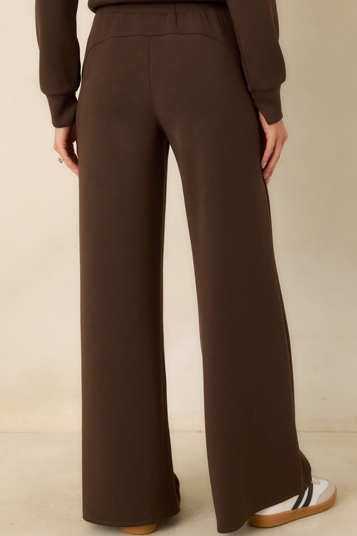 Rear of the brown spacer fabric pants featuring a smooth waistband, relaxed fit, and flowing wide legs.