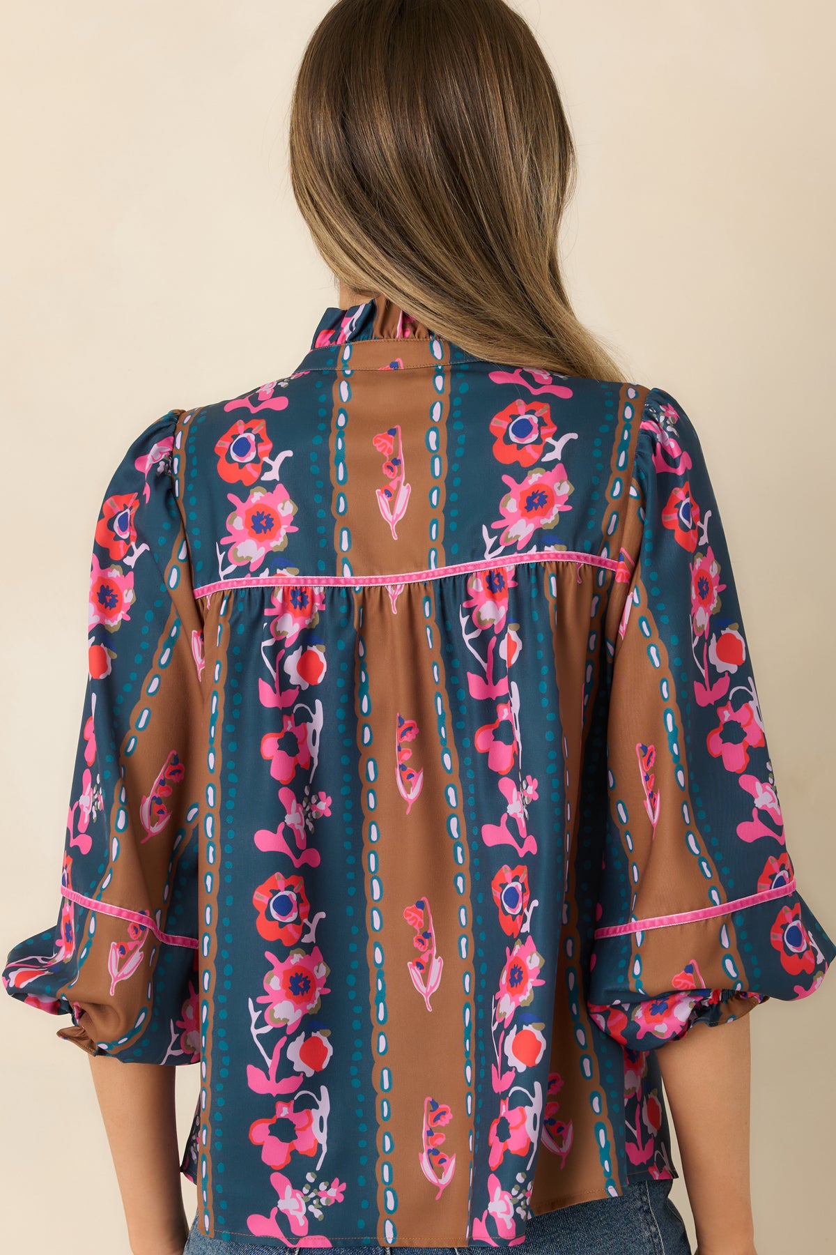 Rear view of the CROSBY Tapestry Stripe blouse with pink-trimmed back yoke, colorful florals, and voluminous balloon sleeves.