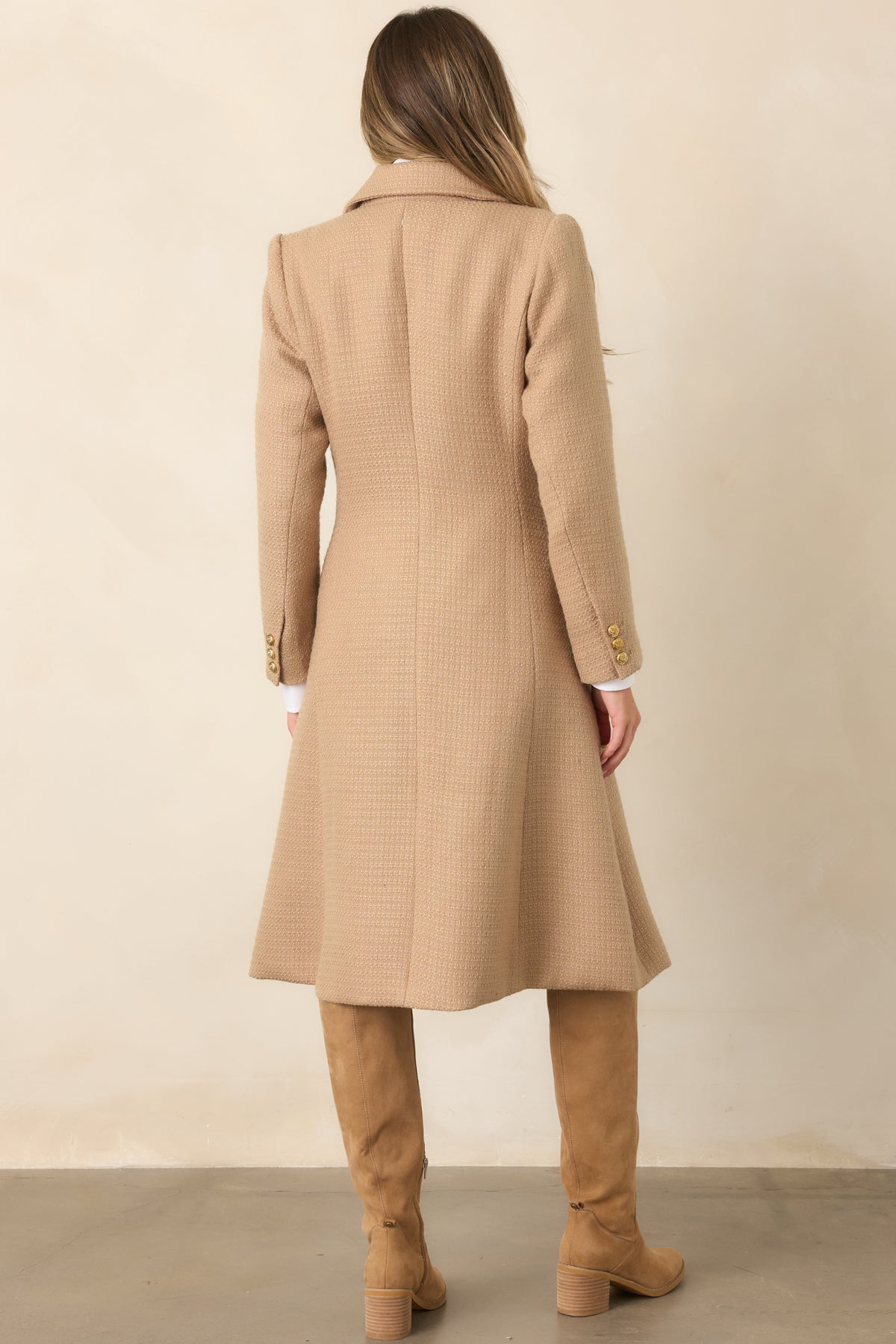 The rear of the camel topcoat showcases its clean structured silhouette and longer tailored length.