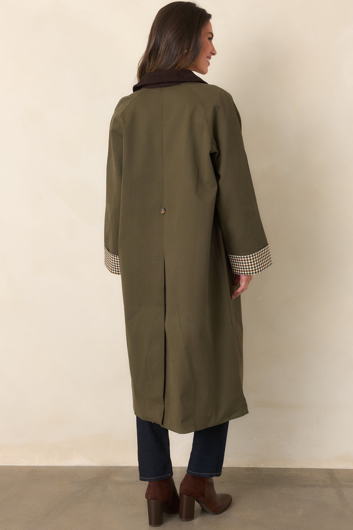 Rear view of the canvas-feel coat showing its long back vent and coordinating tie belt.