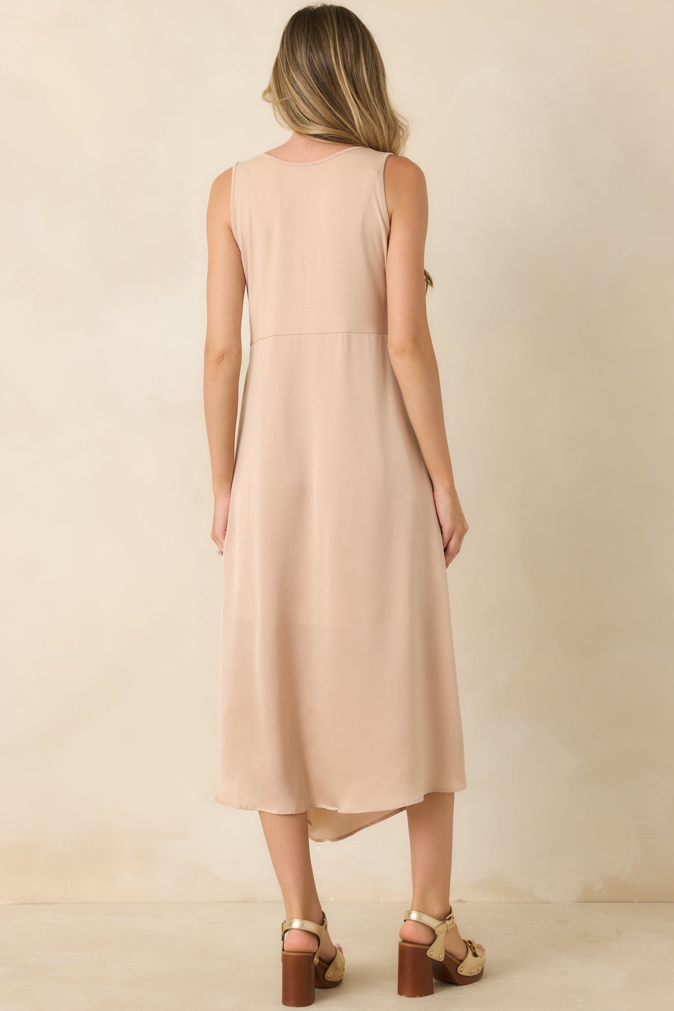 Rear view of the champagne midi dress featuring a sleeveless silhouette, stretch-knit bodice, and flowing satin skirt.
