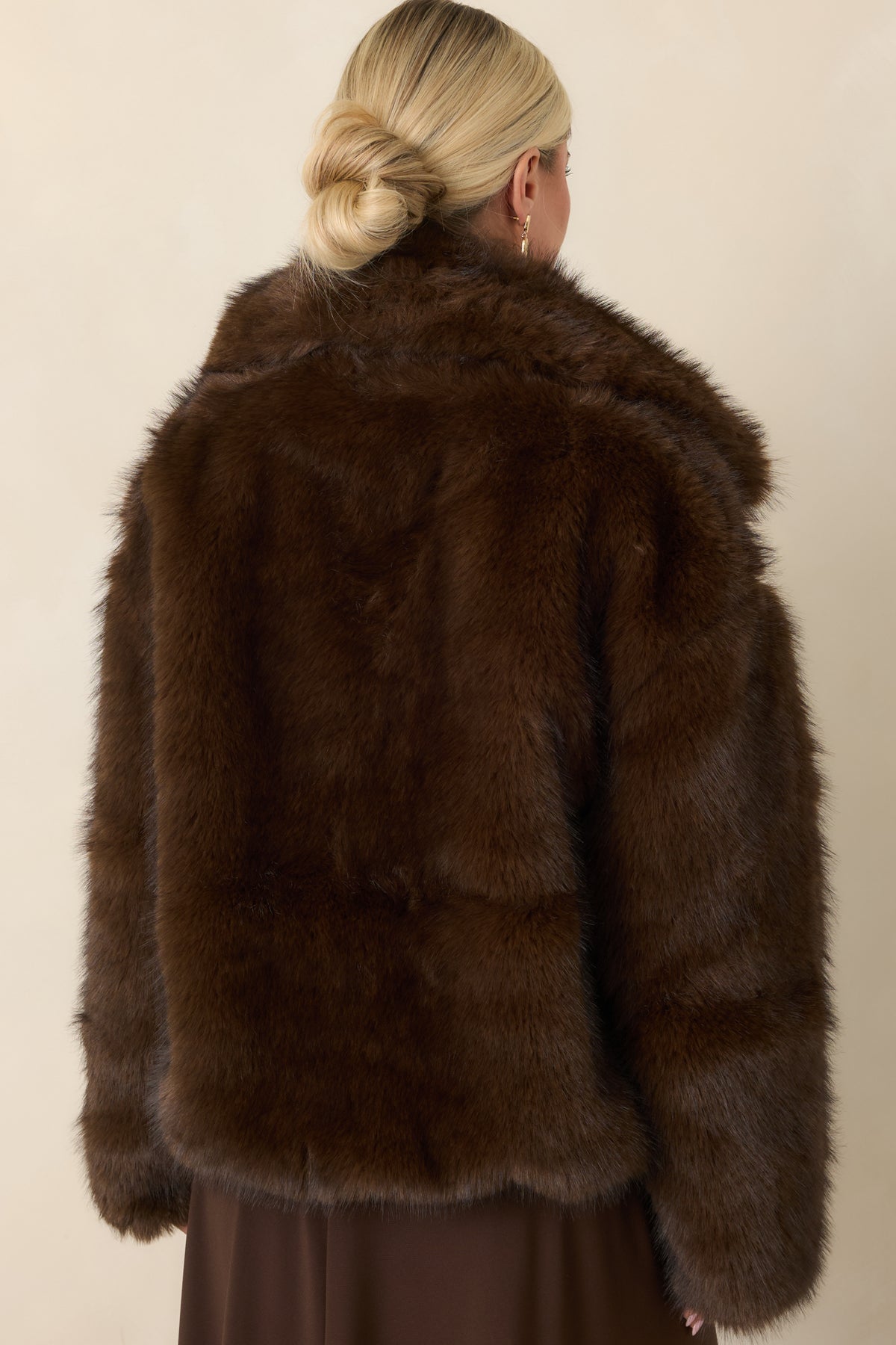 Rear of the chocolate brown faux fur jacket showcasing its relaxed silhouette, long sleeves, and plush texture.