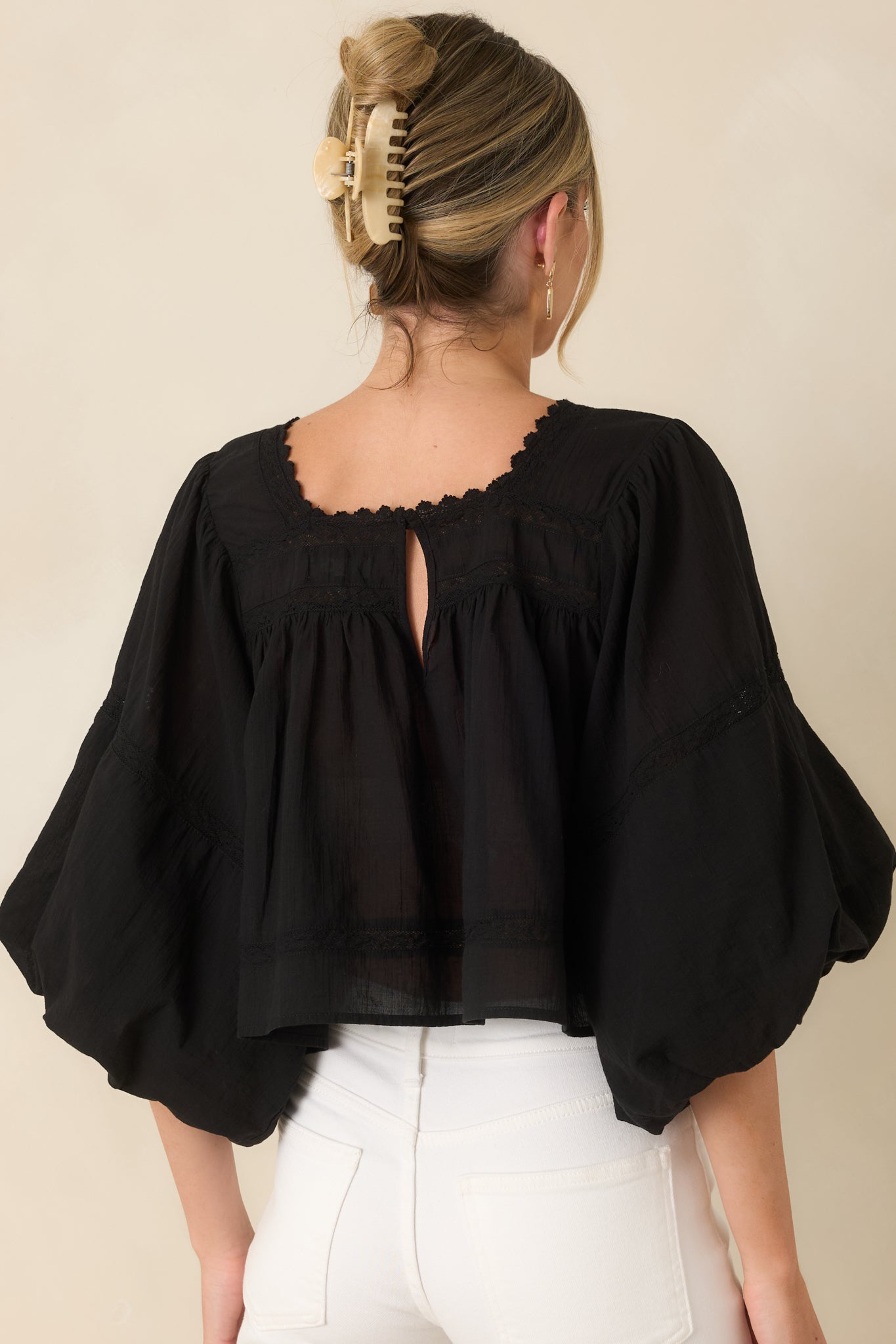 Rear view of the lightweight cotton blouse featuring voluminous puff sleeves and a keyhole button closure at the neckline.
