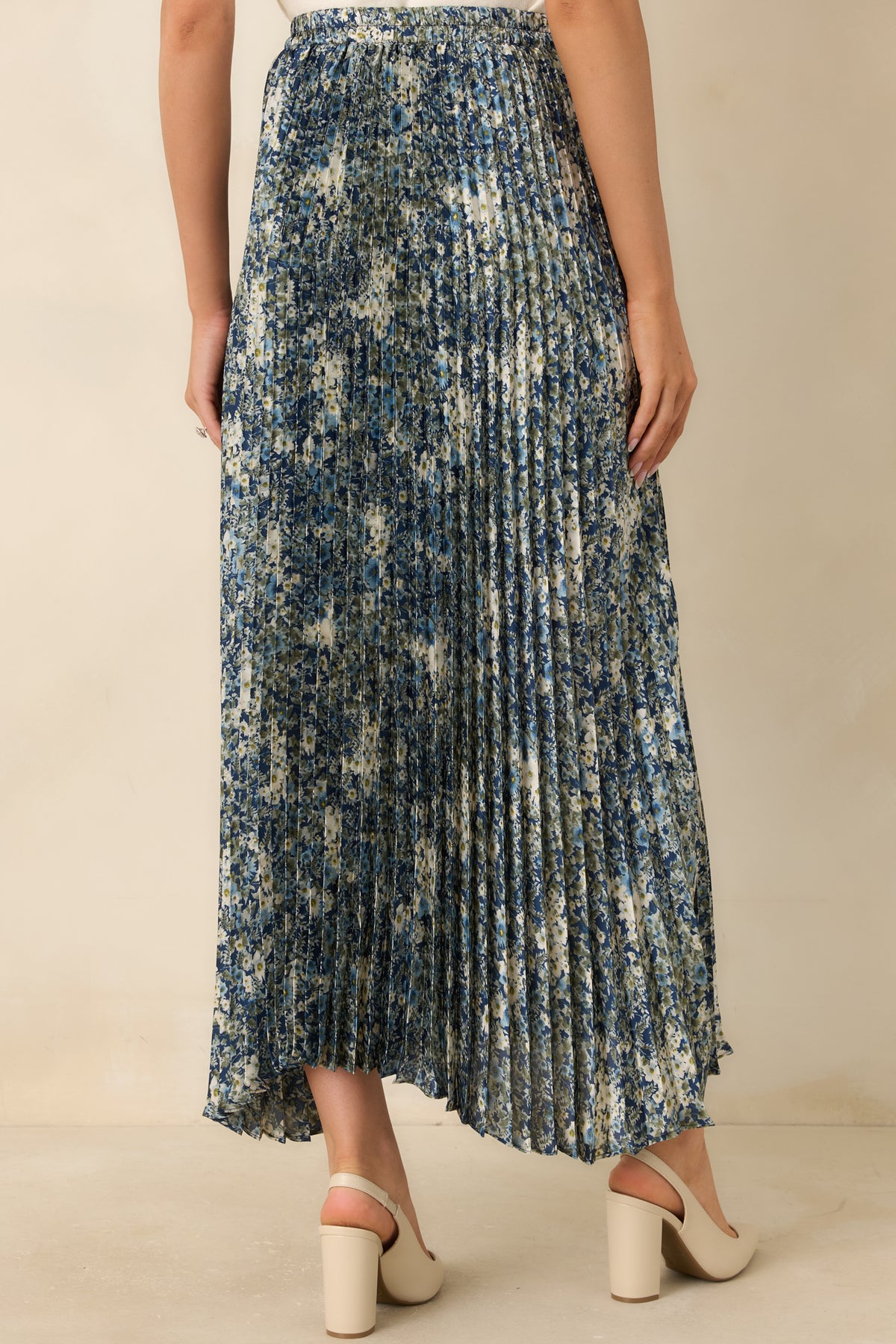 Rear view of the deep blue floral maxi skirt featuring fine accordion pleats and a flowing full-length design.