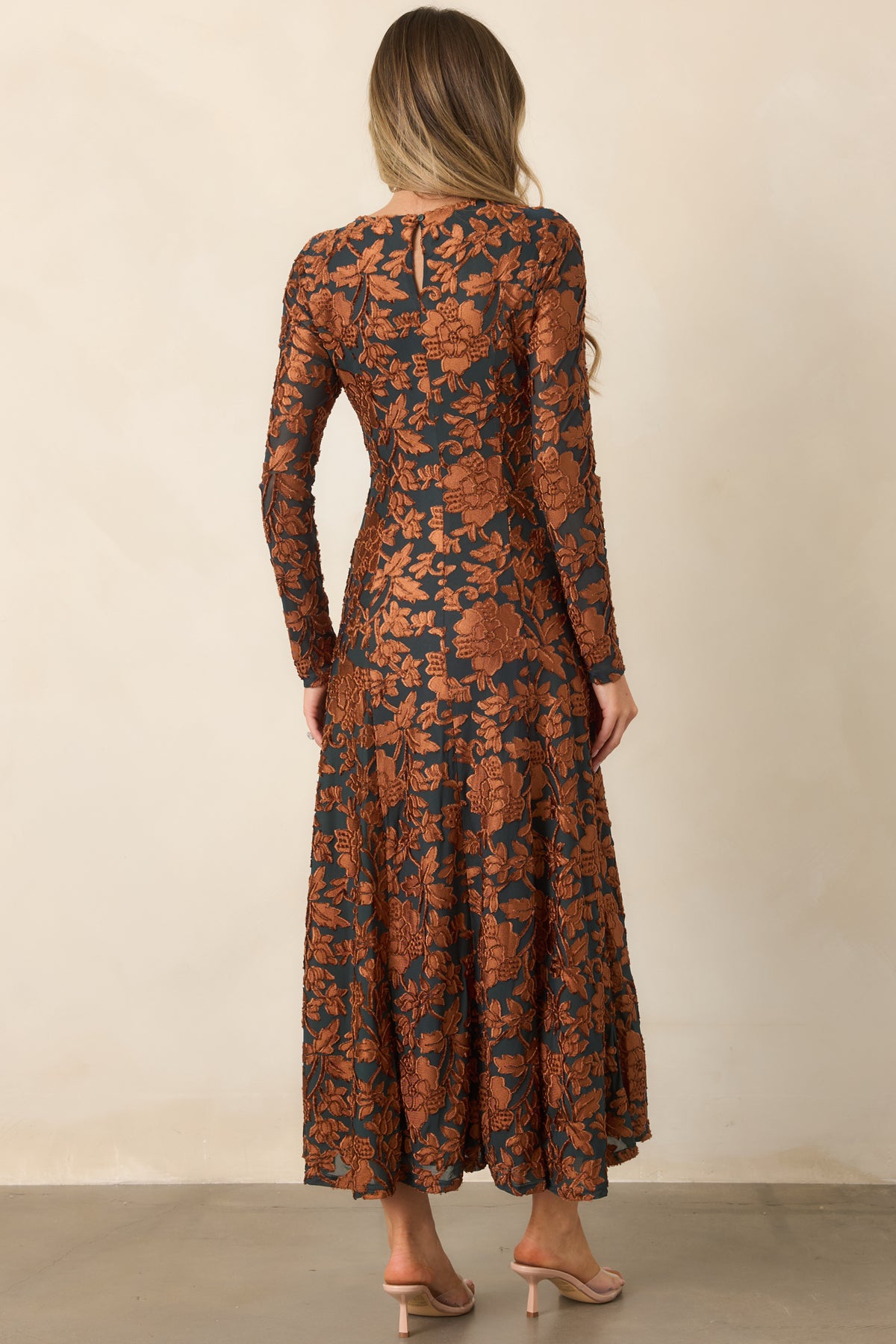 Rear of the deep green floral midi dress showing the button-fastened back keyhole, long sleeves, and flowing skirt.