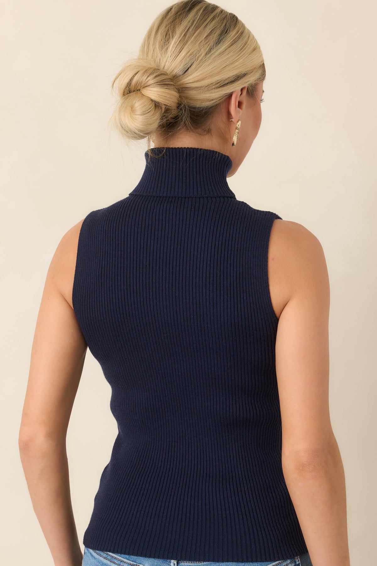 Rear view of the deep navy ribbed knit top showing its fitted silhouette, sleeveless cut, and hip-length hem.