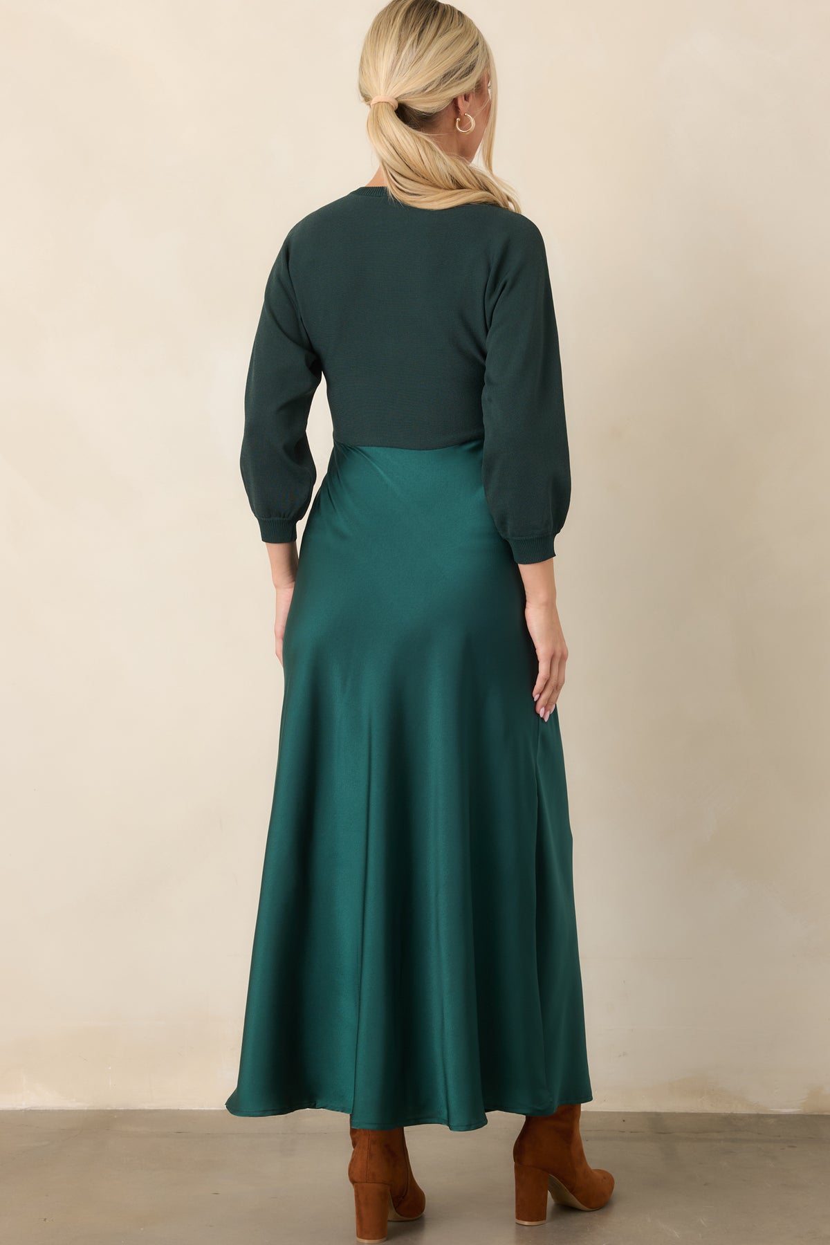 Rear of the emerald dress showing the fitted knit bodice, three-quarter sleeves, high waist, and flowing satin A-line skirt.