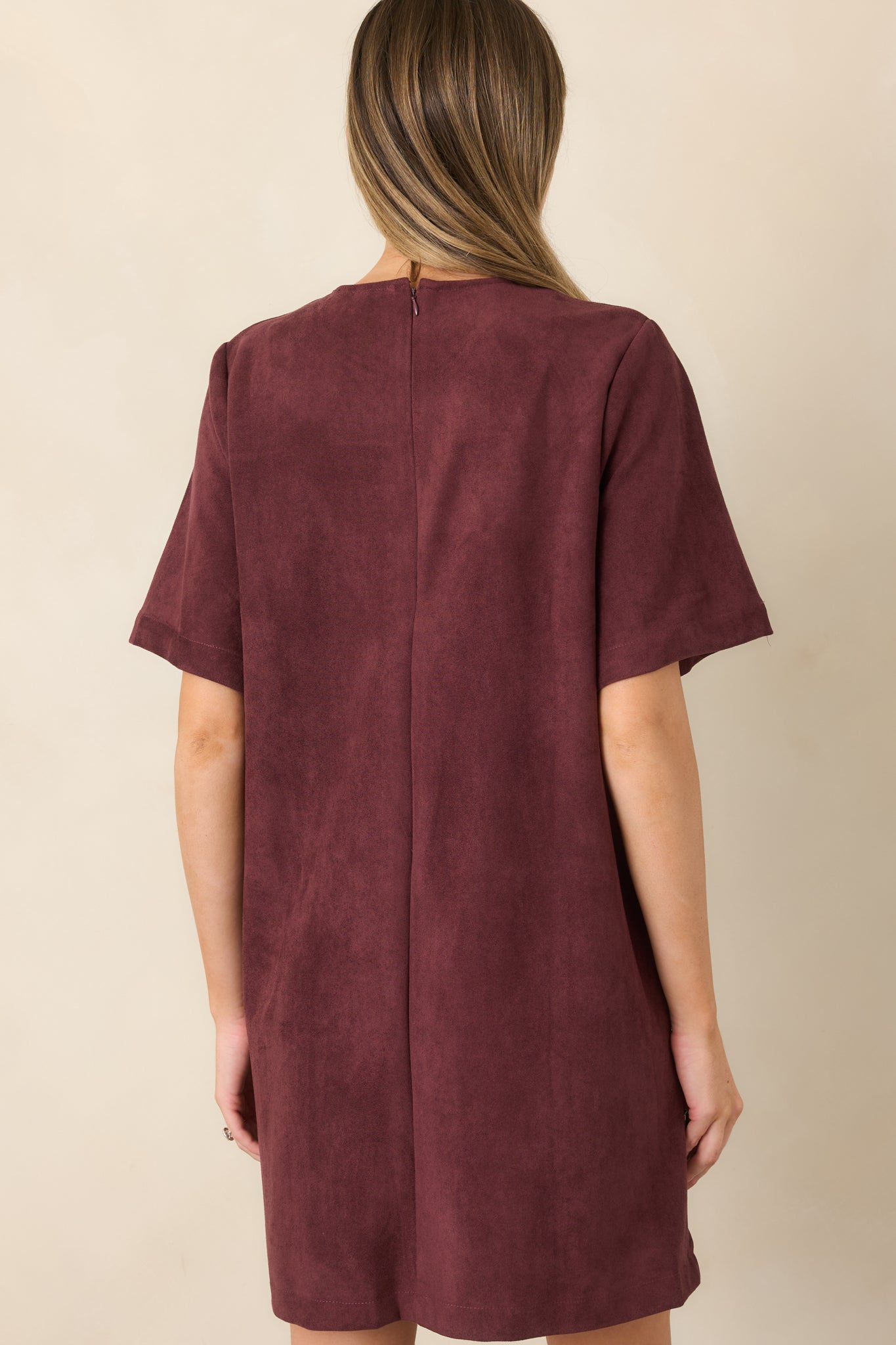 Rear view of the faux suede mini dress showcasing its short sleeves, smooth fitted silhouette, back zipper closure, and clean finish.