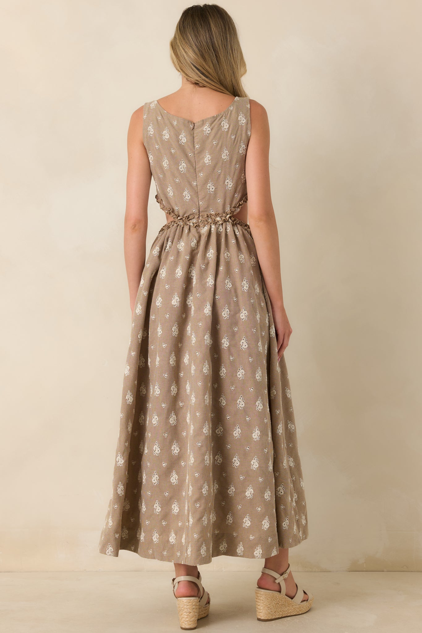 Rear view of the sleeveless maxi dress featuring a flowing skirt, floral eyelet print, and ruffle-trimmed side cut-out detailing.
