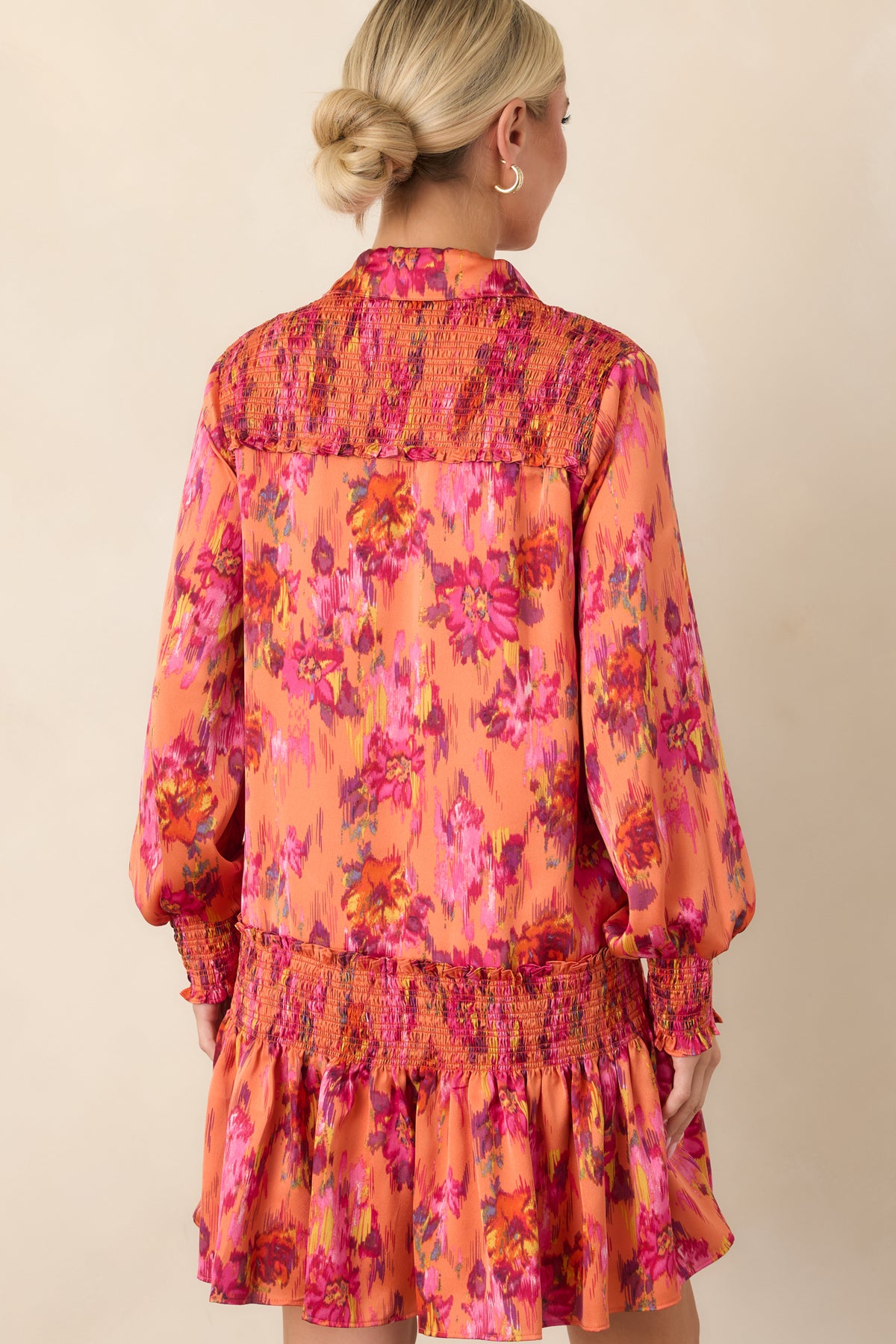 Rear view of the floral satin mini dress showcasing the smocked drop waist, voluminous balloon sleeves, fitted cuffs, and flouncy skirt.