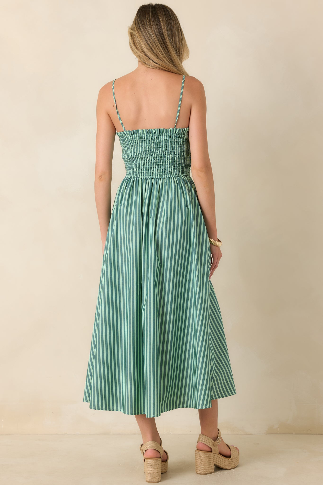 Rear view of the green and ivory striped maxi dress featuring adjustable tie-back straps, a comfortable smocked back panel, and a flowing full skirt.