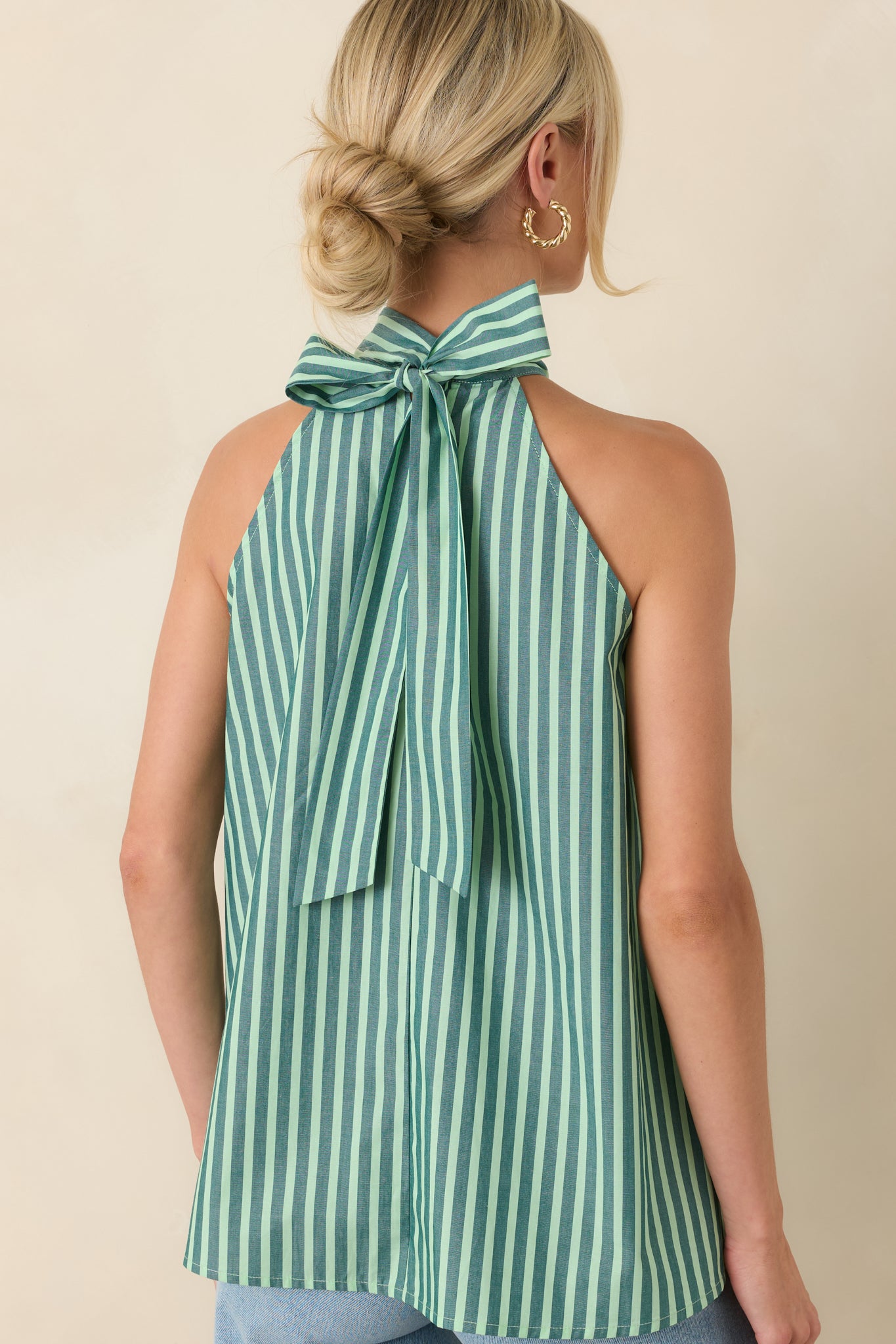 Rear view of the lightweight cotton halter top highlighting the self-tie back closure, sleeveless design, and alternating dark green and mint stripes.